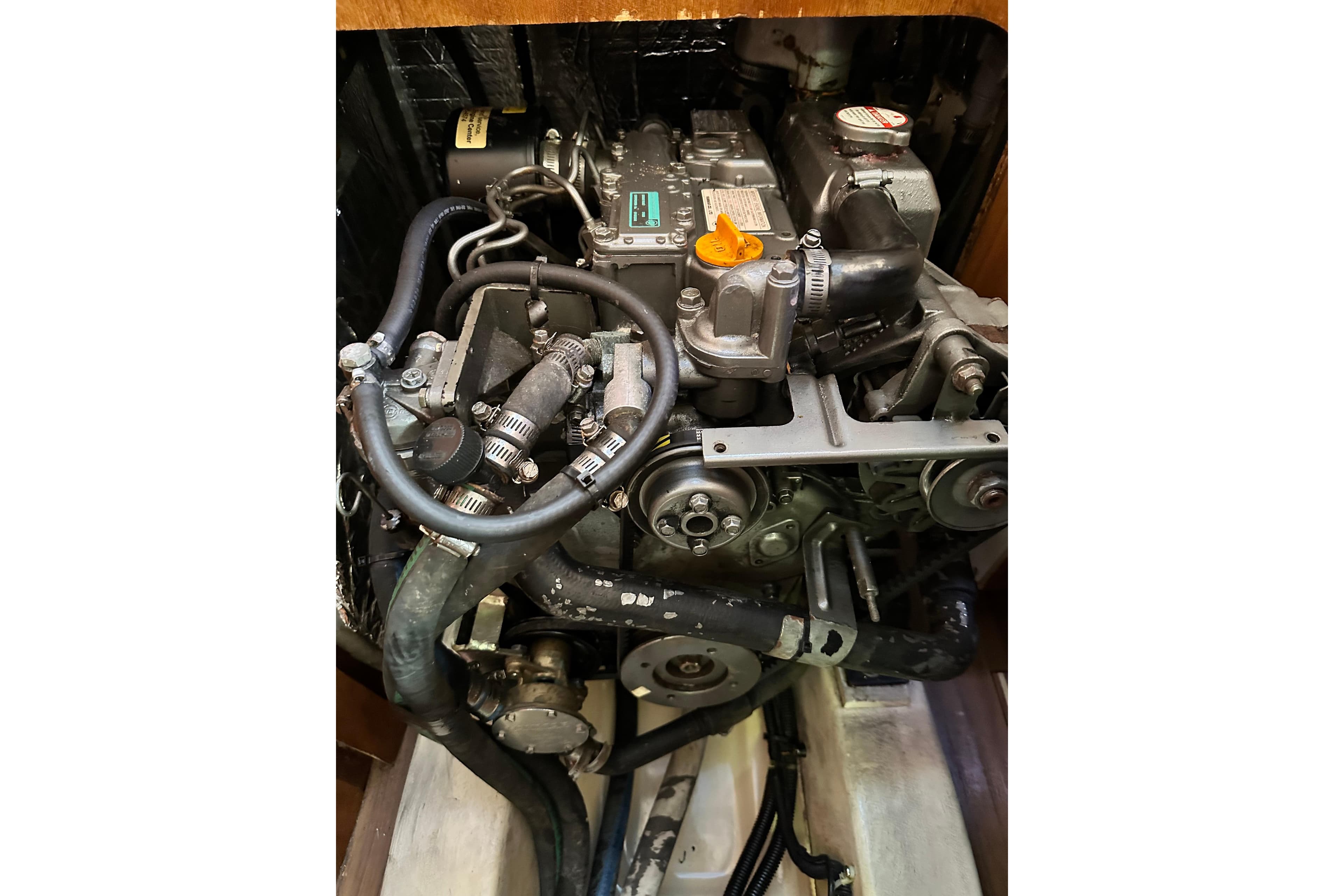 Engine compartment of a 2008 Hunter 33 sailboat, showcasing mechanical components and hoses.