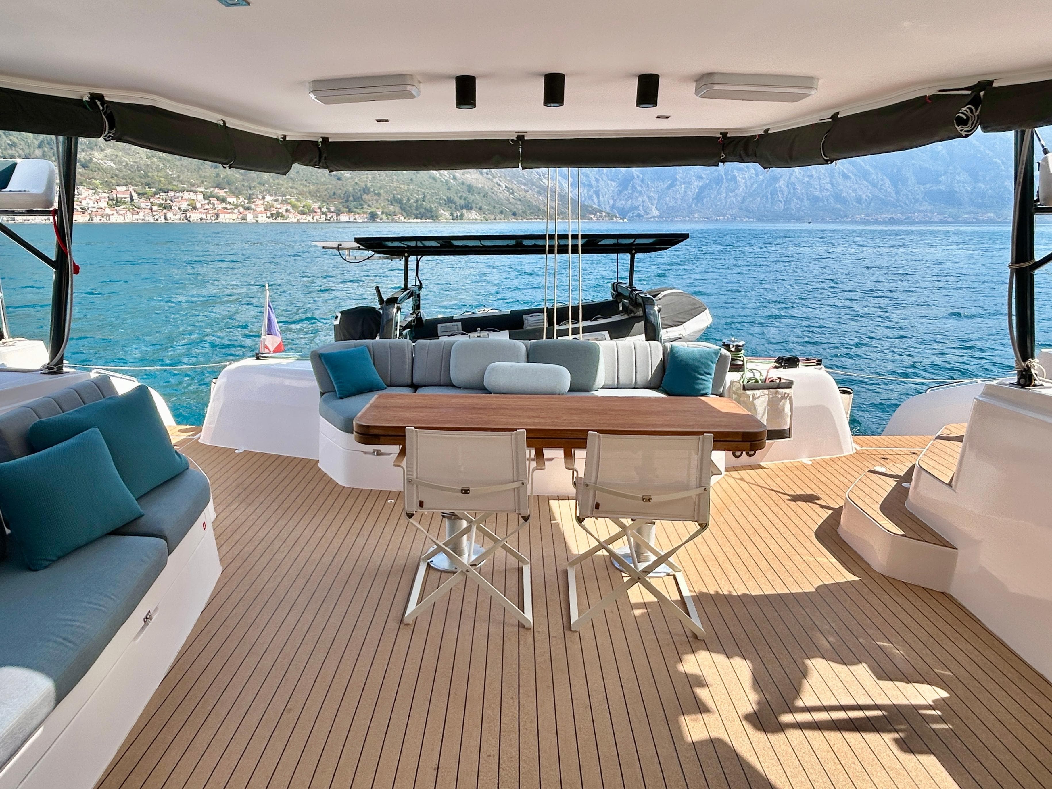 Luxurious 2022 Outremer 55 yacht deck with seating, table, and stunning ocean view.