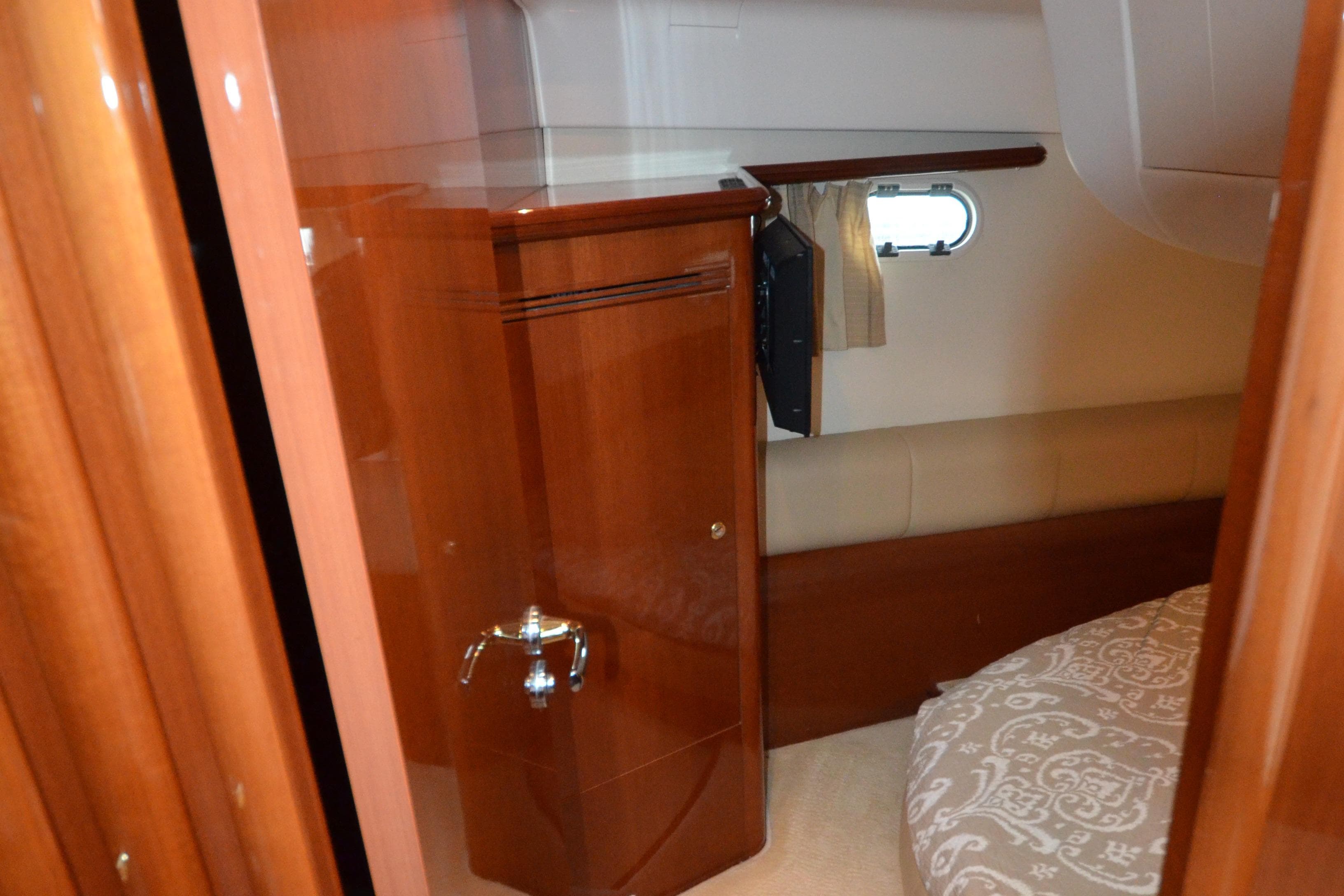 Interior cabin of 2007 Jeanneau Prestige 46 yacht with wooden cabinetry and porthole.