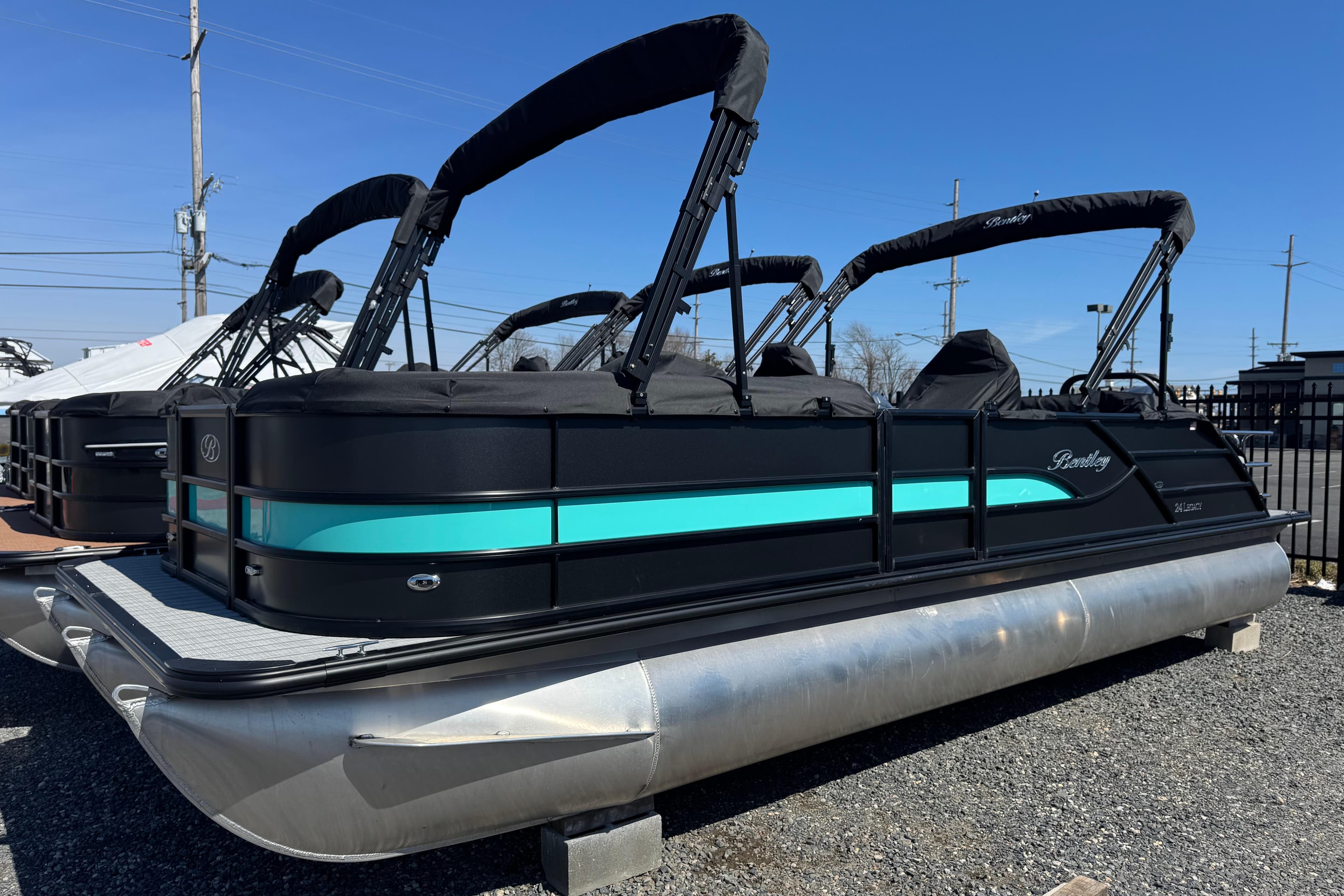 2026 Bentley Pontoons Legacy 243 Swingback, sleek black and teal design, parked outdoors.