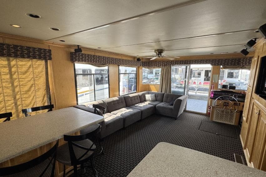 Luxurious houseboat interior with modern seating, large windows, and a steering wheel, 2006 model.