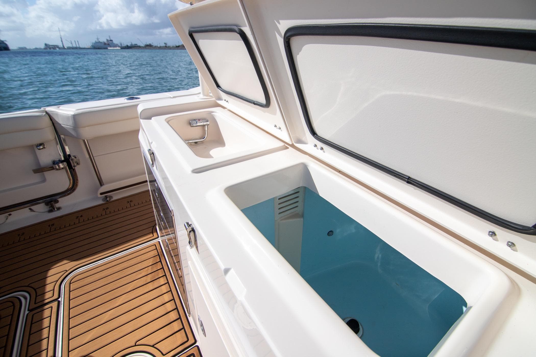 2023 Grady-White Canyon 326 boat interior with open storage compartment, docked by the sea.