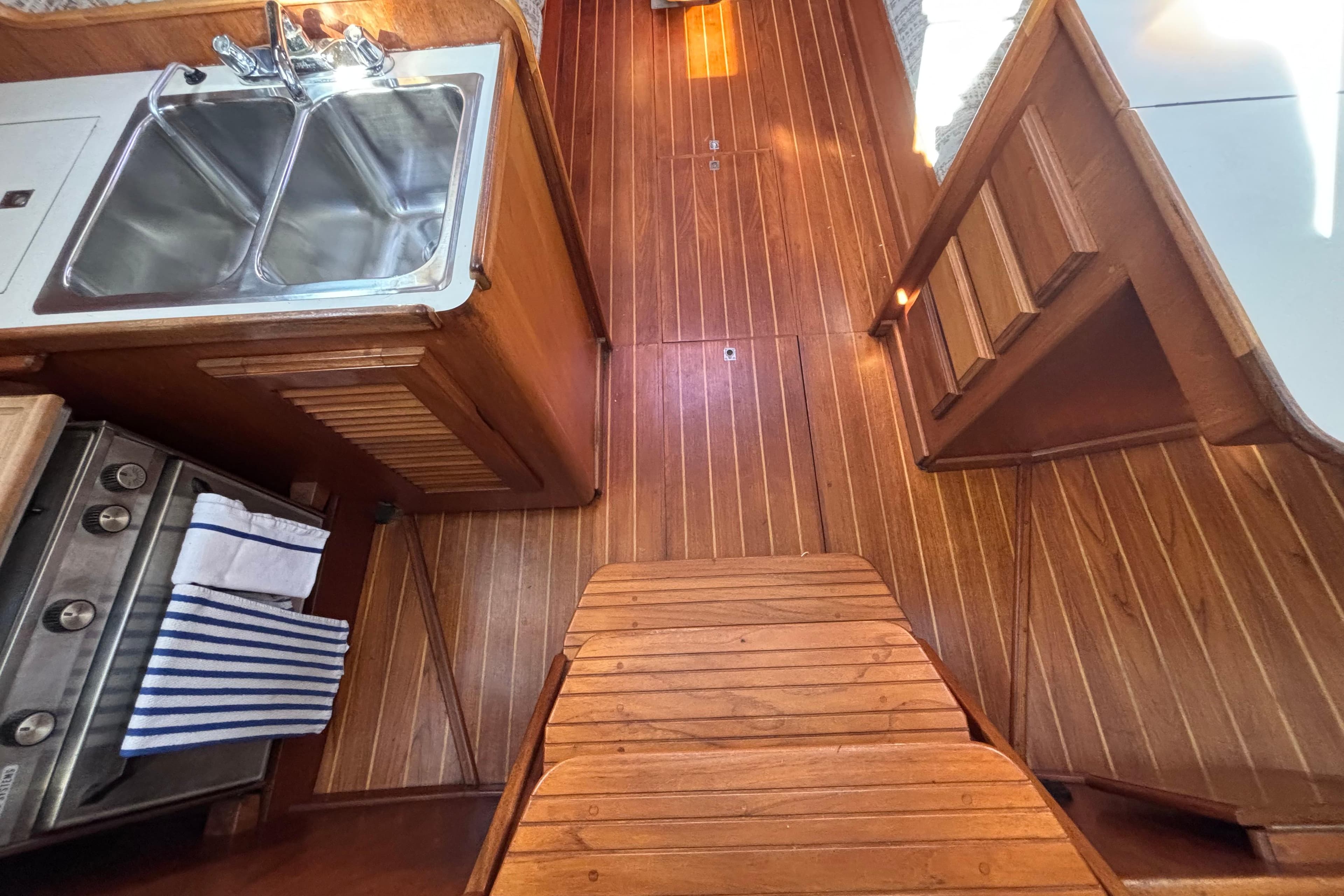 Wooden interior of 1979 Islander Peterson 40 sailboat with sink and stove.