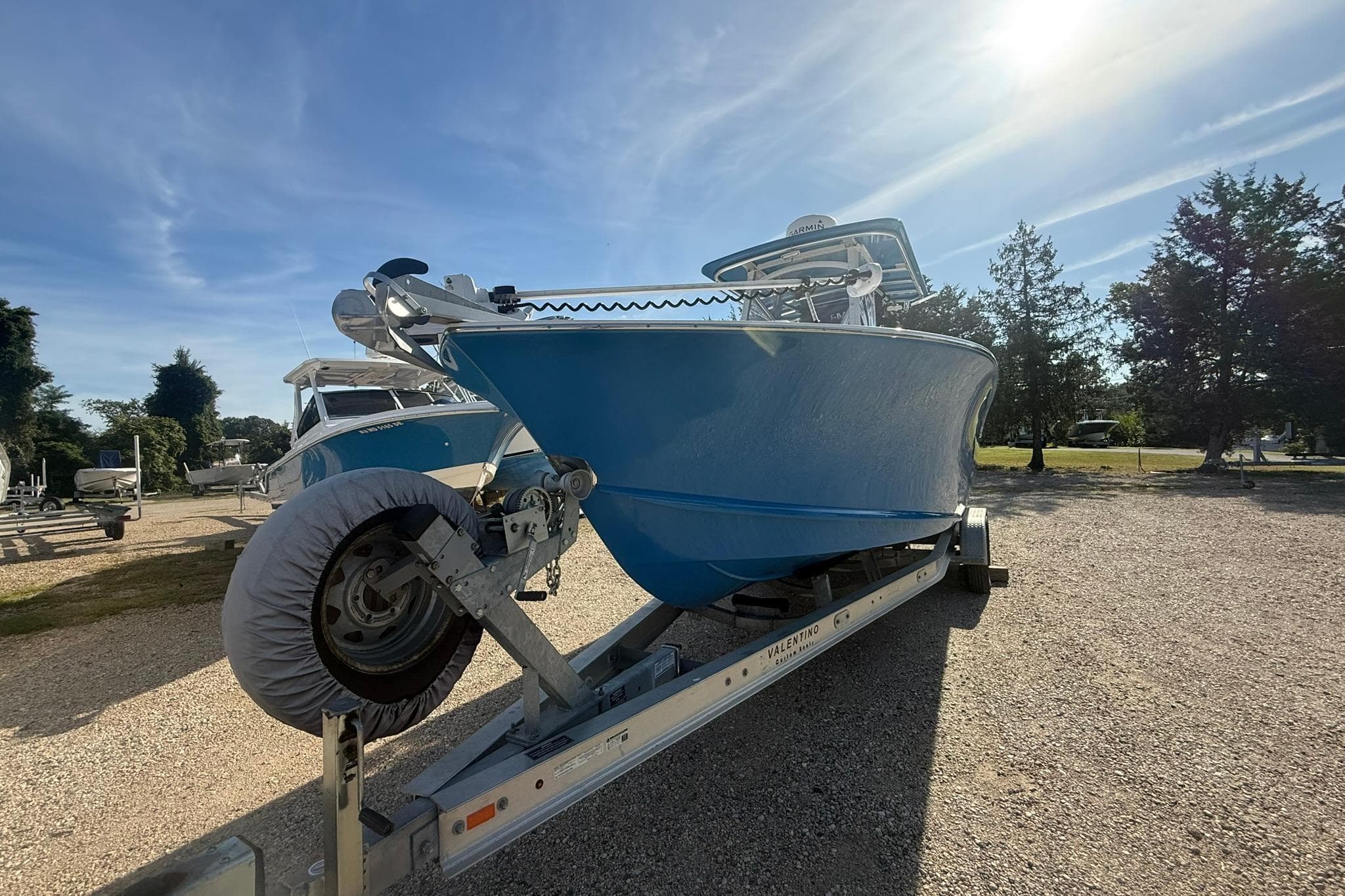 Blue 2020 Valentino 28CC boat on trailer under sunny sky.