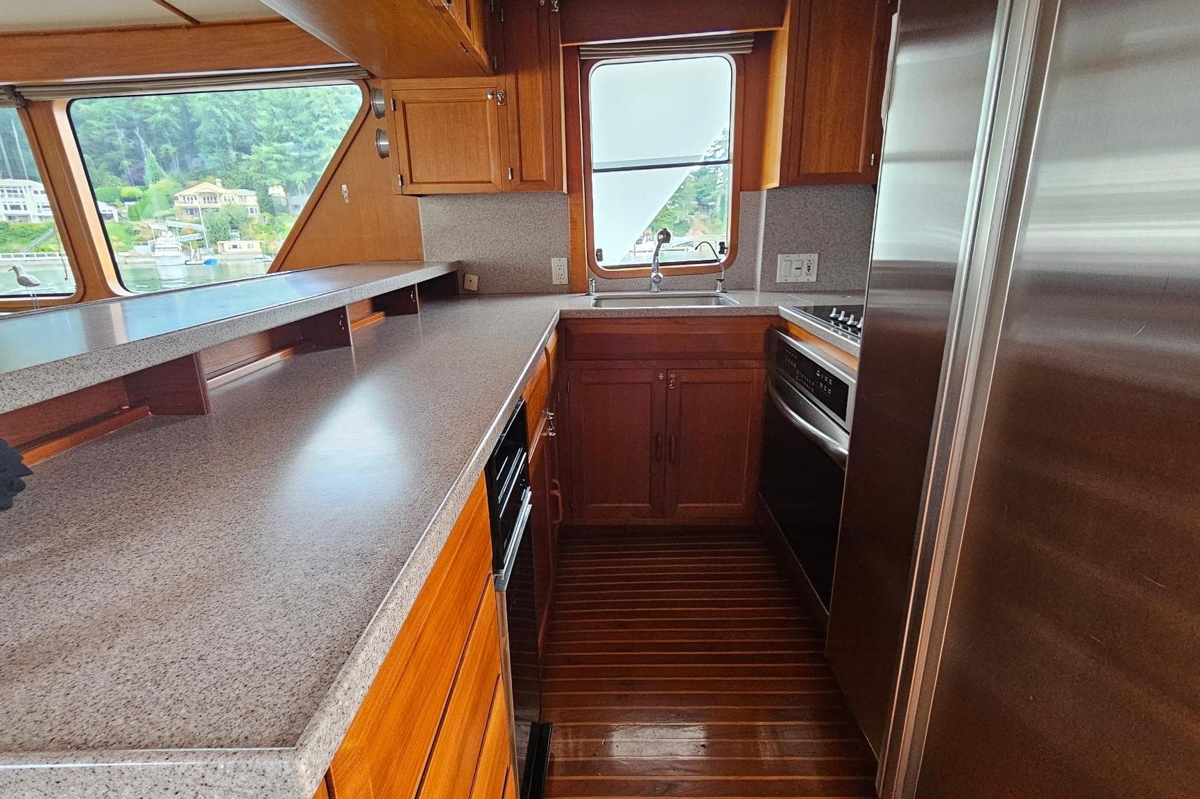 1987 DeFever 53 POC yacht kitchen with wood cabinetry, stainless steel appliances, and large windows.