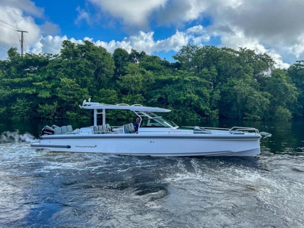 2024 Axopar 37 Sun Top cruising on a river with lush green trees in the background.