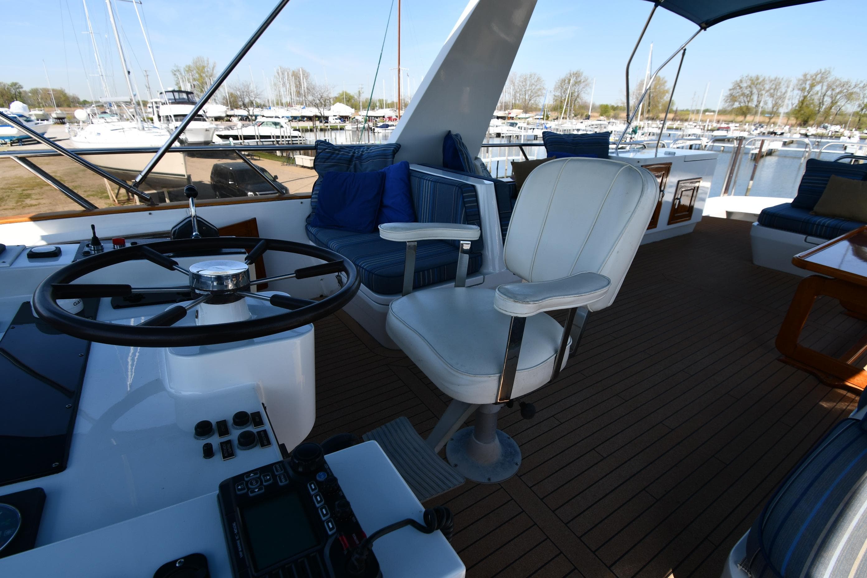 1986 Lowland 64 Pilot House Long Range Motor Yacht helm station with white captain's chair and marina view.