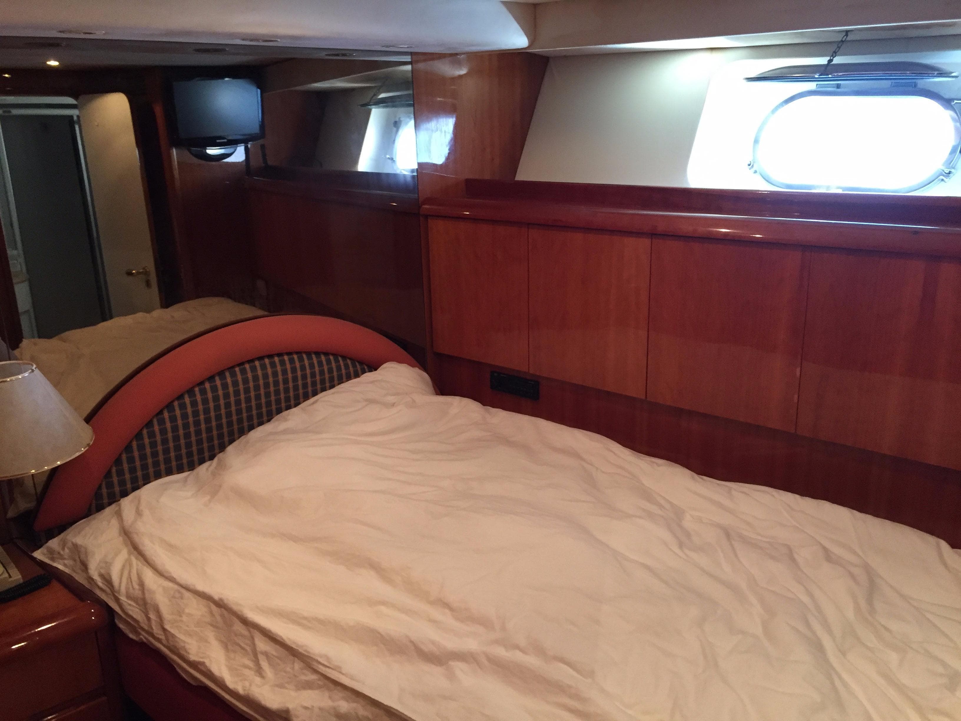 Luxurious cabin interior of 1994 Falcon 76 yacht with bed and porthole window.