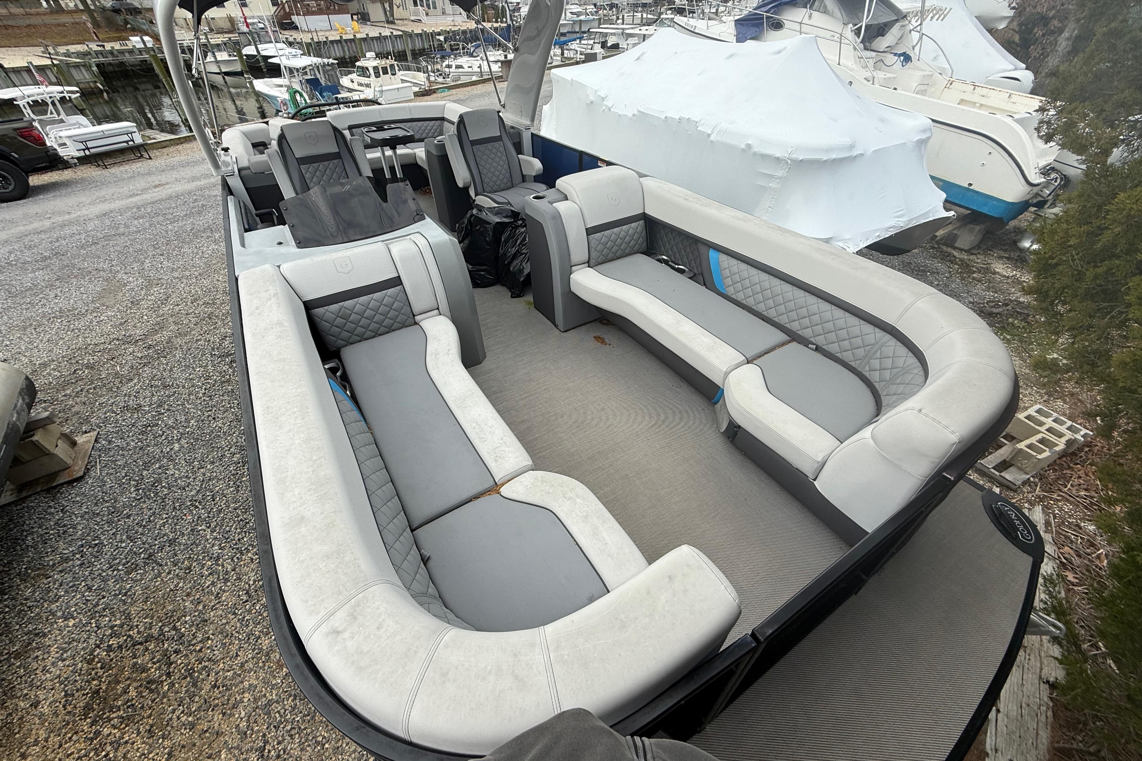 2023 Godfrey AquaPatio 255 ULC pontoon boat with spacious seating, docked at marina.