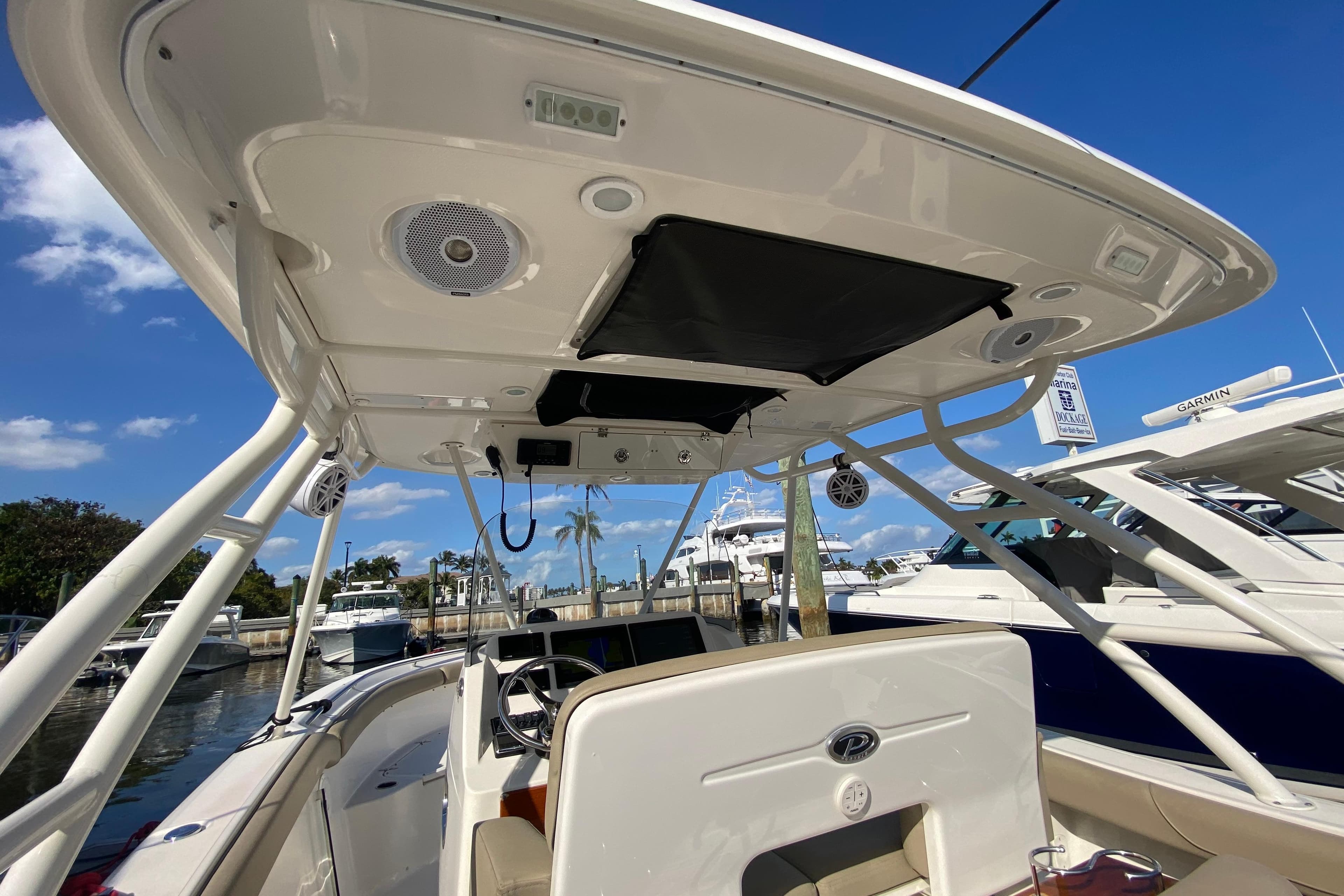 2015 Pursuit S 280 Sport boat interior with canopy and docked yachts in background.