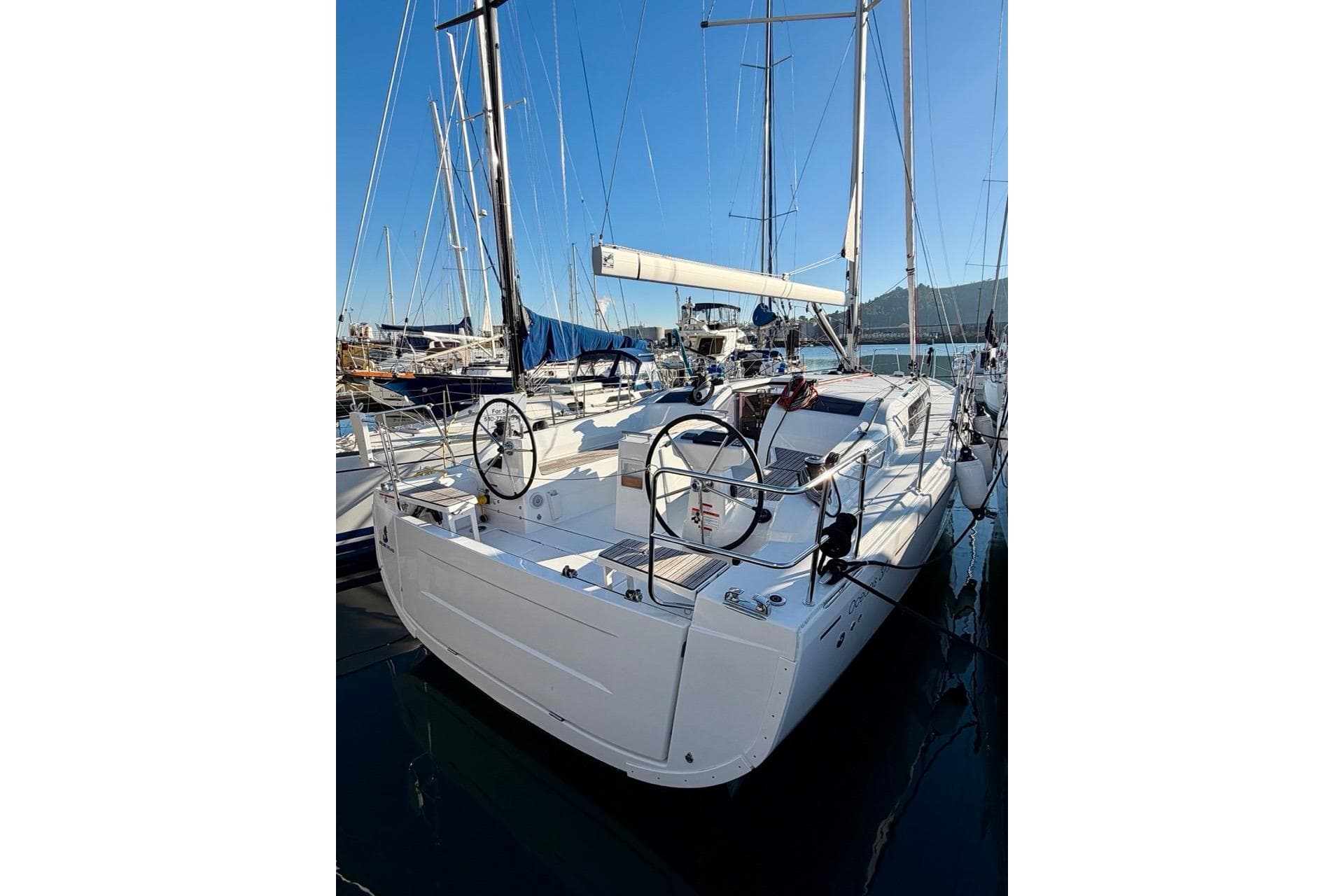 2025 Beneteau Oceanis 37.1 sailboat docked in a marina, showcasing dual steering wheels.