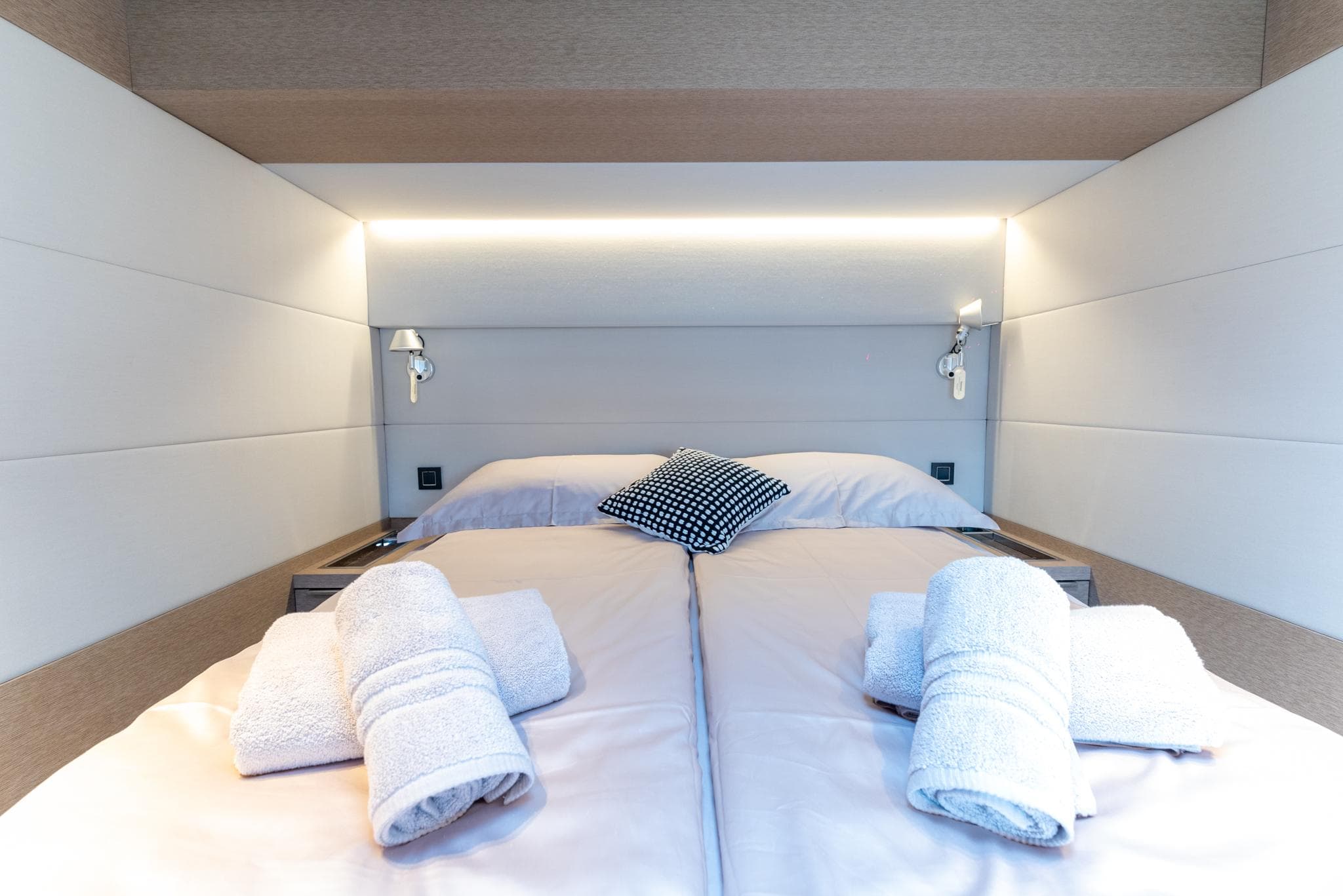 Luxurious bedroom interior of 2024 Lagoon SIXTY 5 yacht with neatly arranged towels.