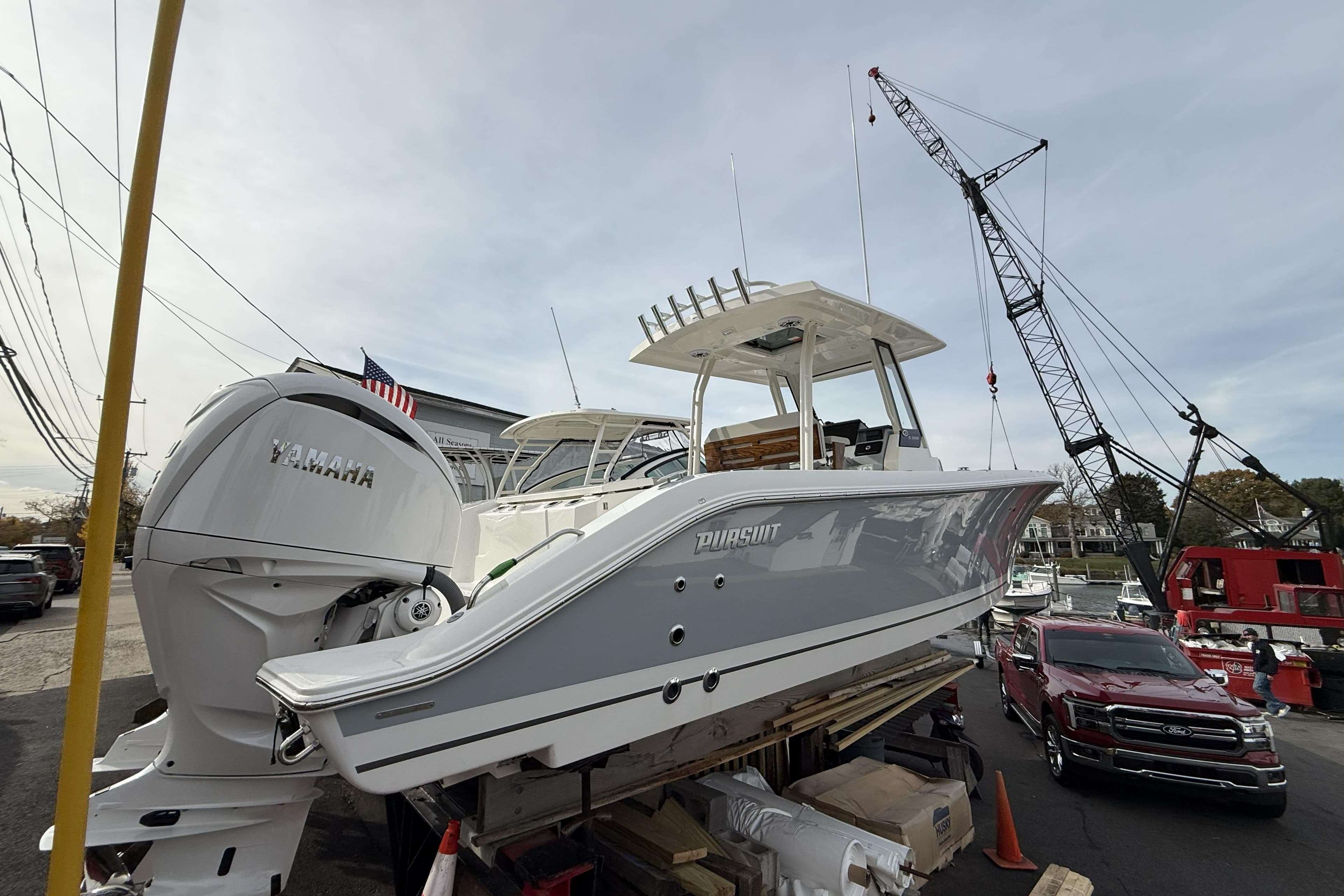 2026 Pursuit S 288 Sport boat with Yamaha engine on display near crane.