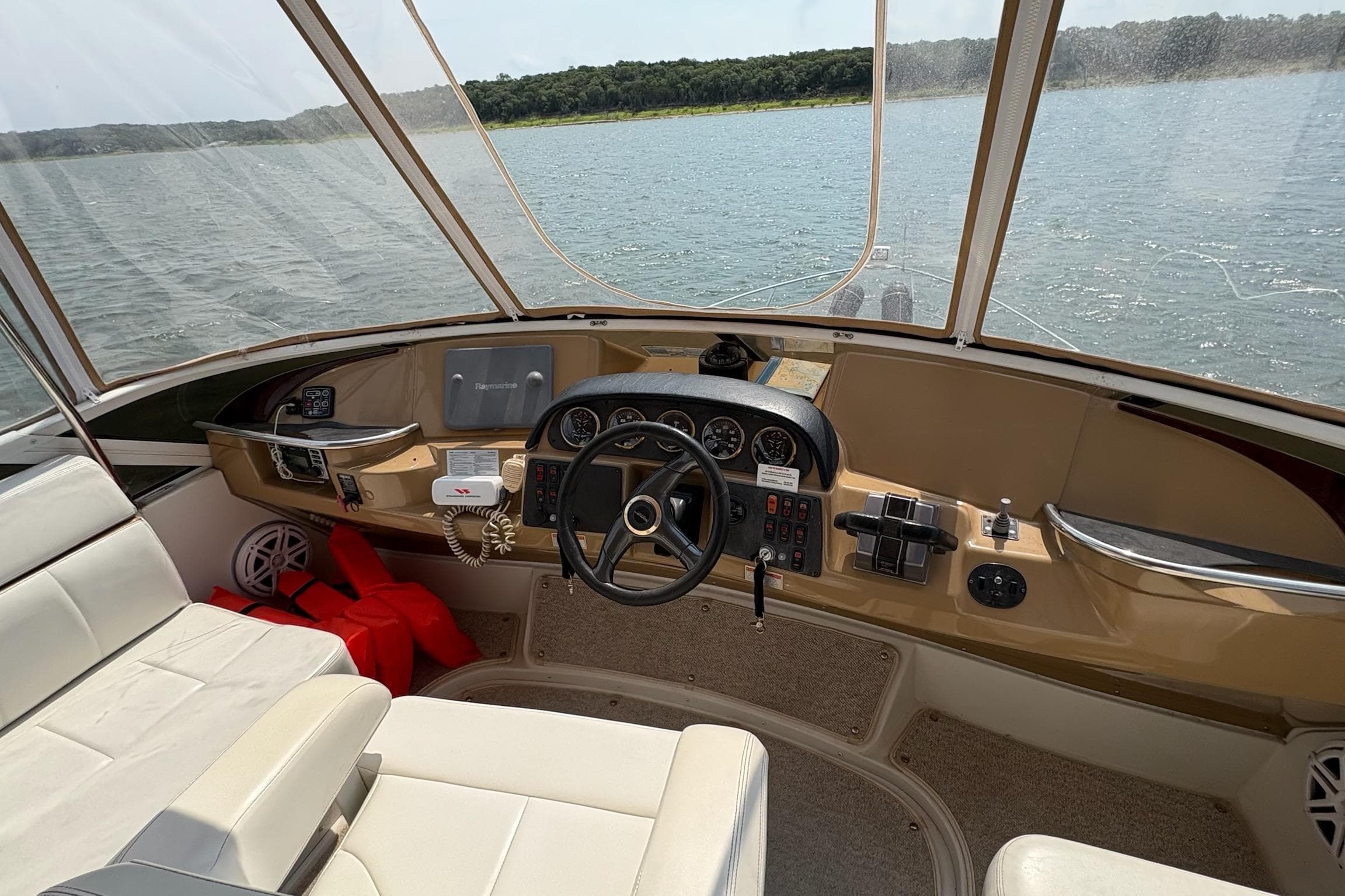 2003 Carver 396 Motor Yacht helm with steering wheel, gauges, and lake view.