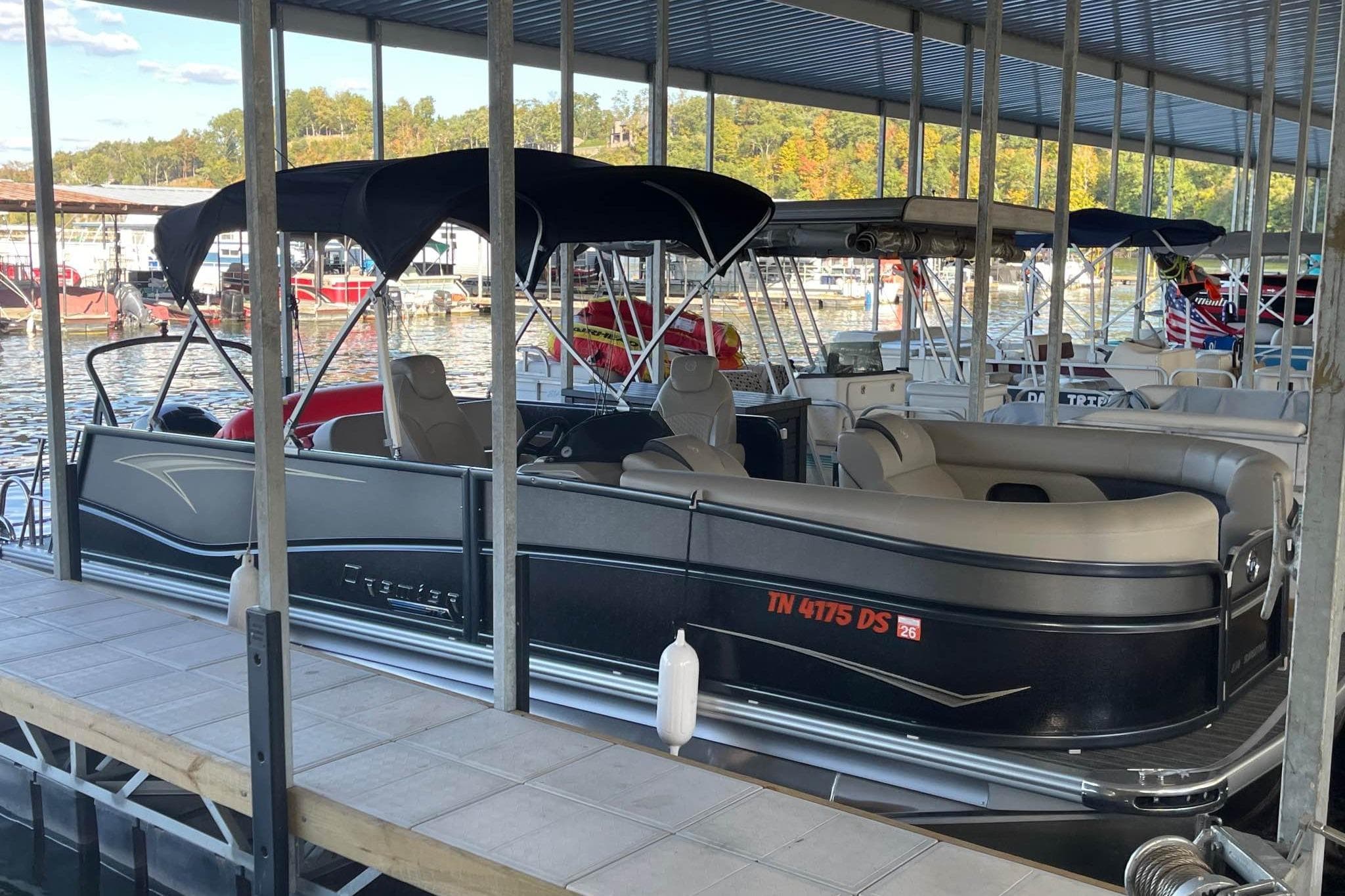 2023 Premier Sunsation pontoon boat docked in a marina under a covered structure.