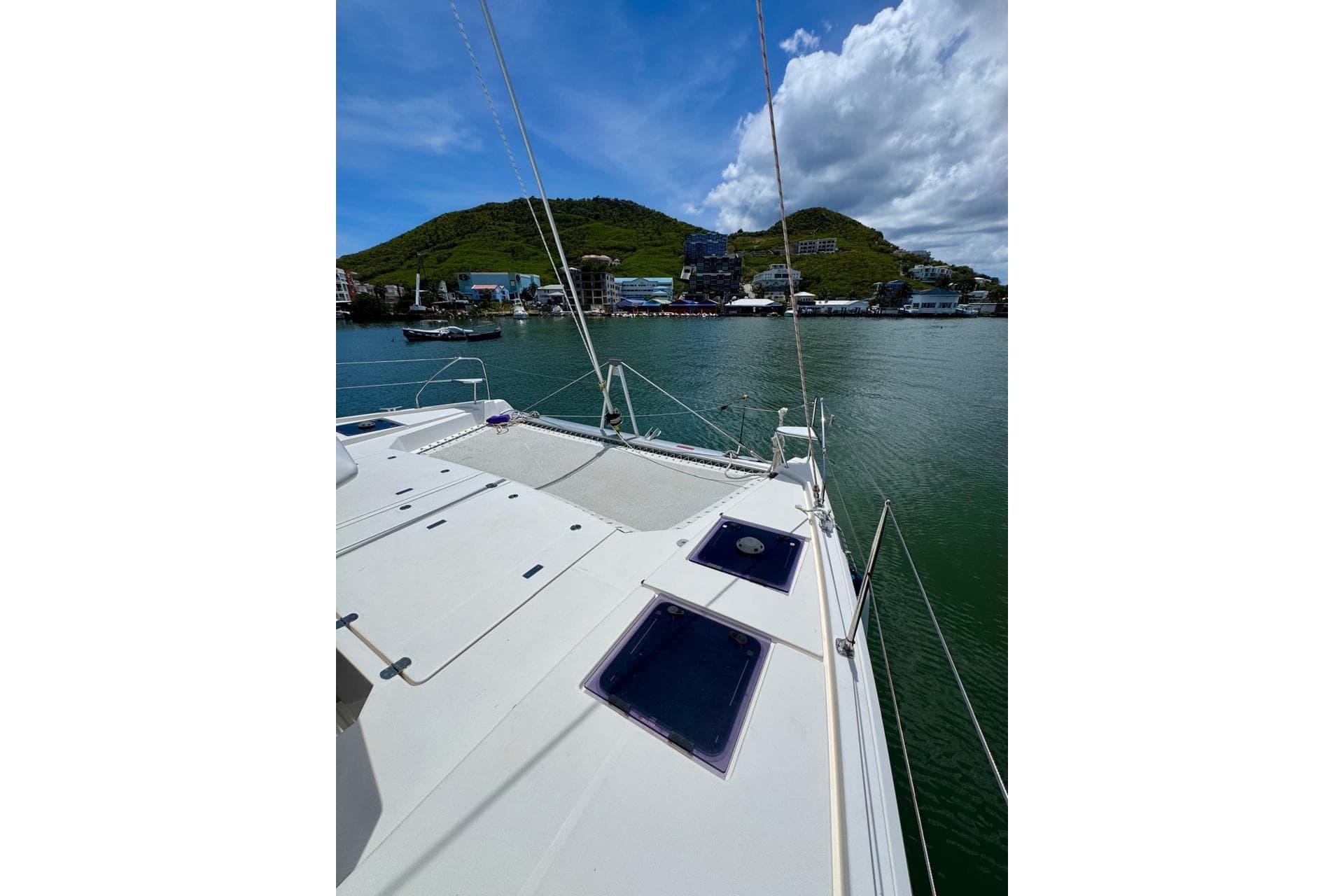 2017 Leopard 45 catamaran docked in scenic harbor with lush hills and blue sky.