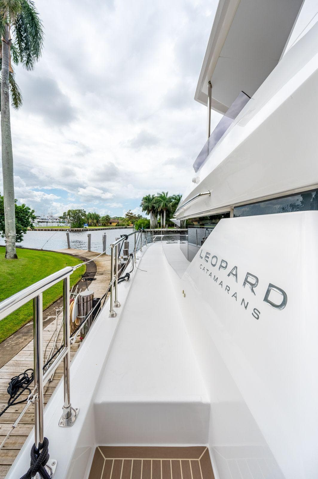 2024 Leopard 53 Powercat yacht docked by lush greenery.