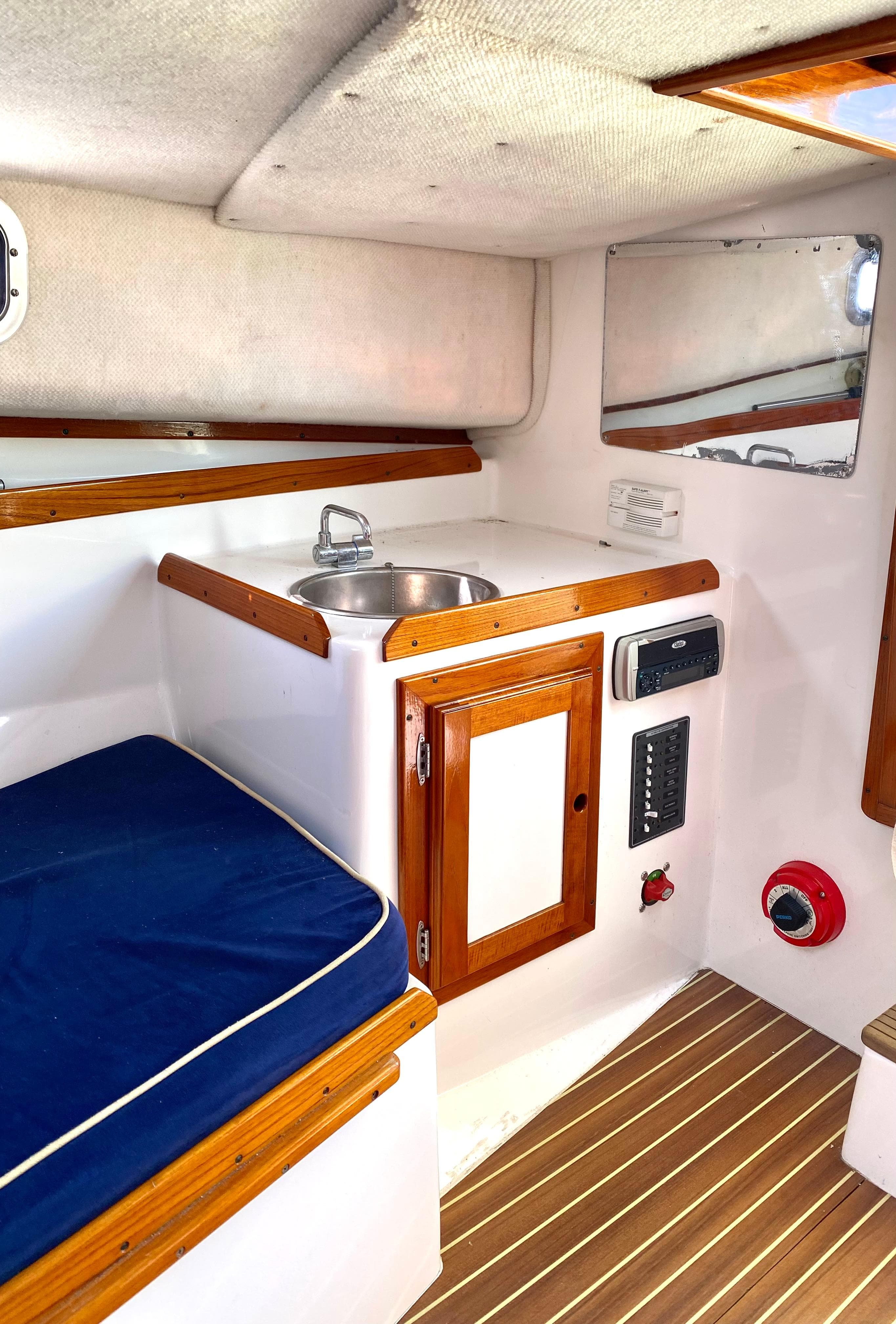 Interior of 2003 Surf-Hunter 25 boat with sink, wooden cabinetry, and blue cushioned seating.