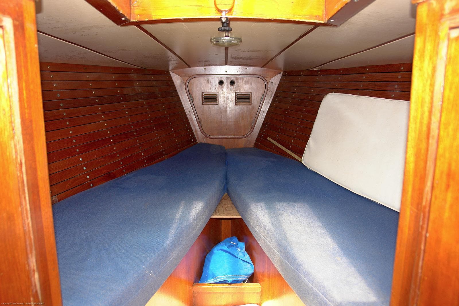 Interior cabin of 1973 Nautor Swan 44 sailboat with wooden paneling and blue cushions.