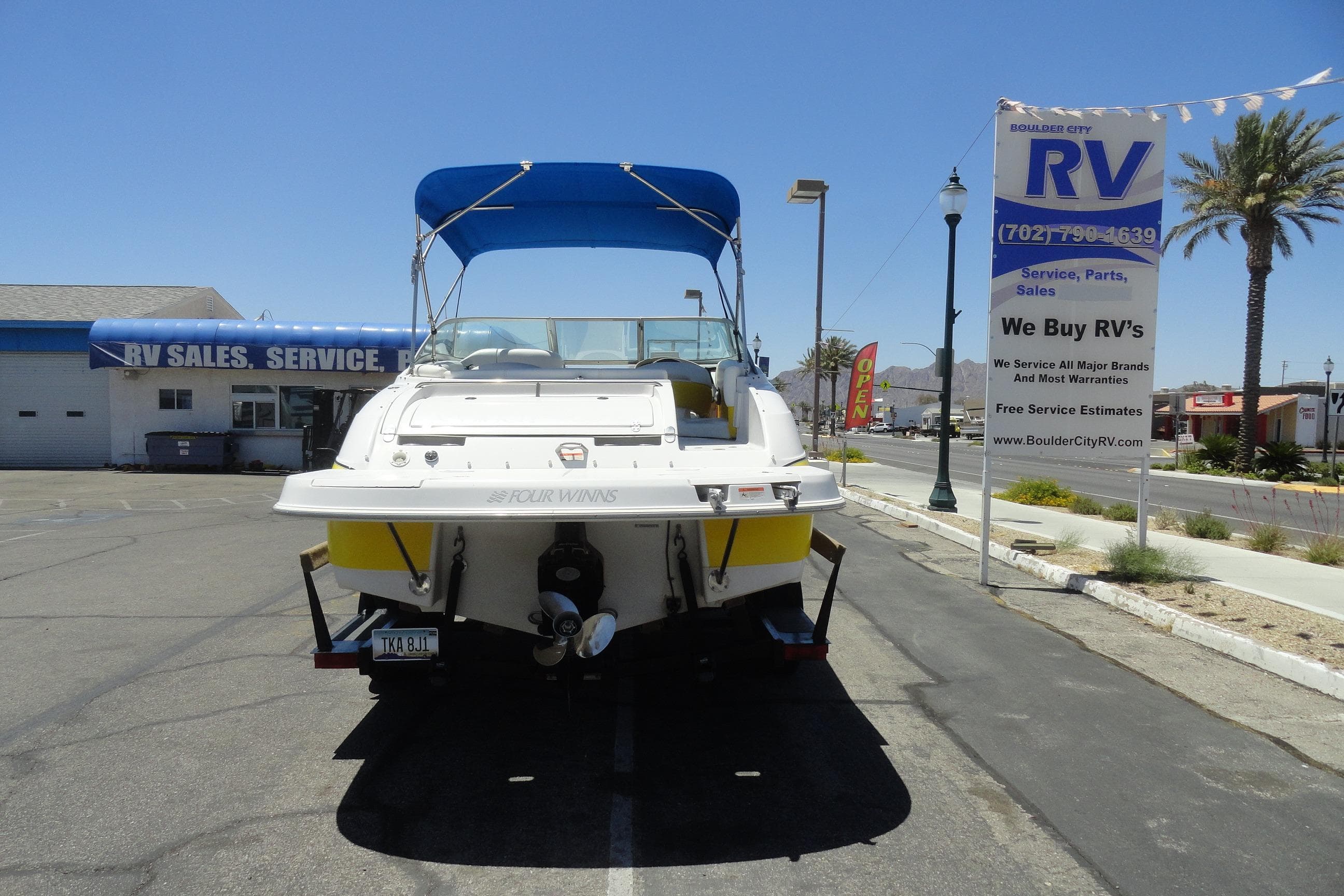 2005 Four Winns 214 Funship boat parked at RV sales lot under blue canopy.