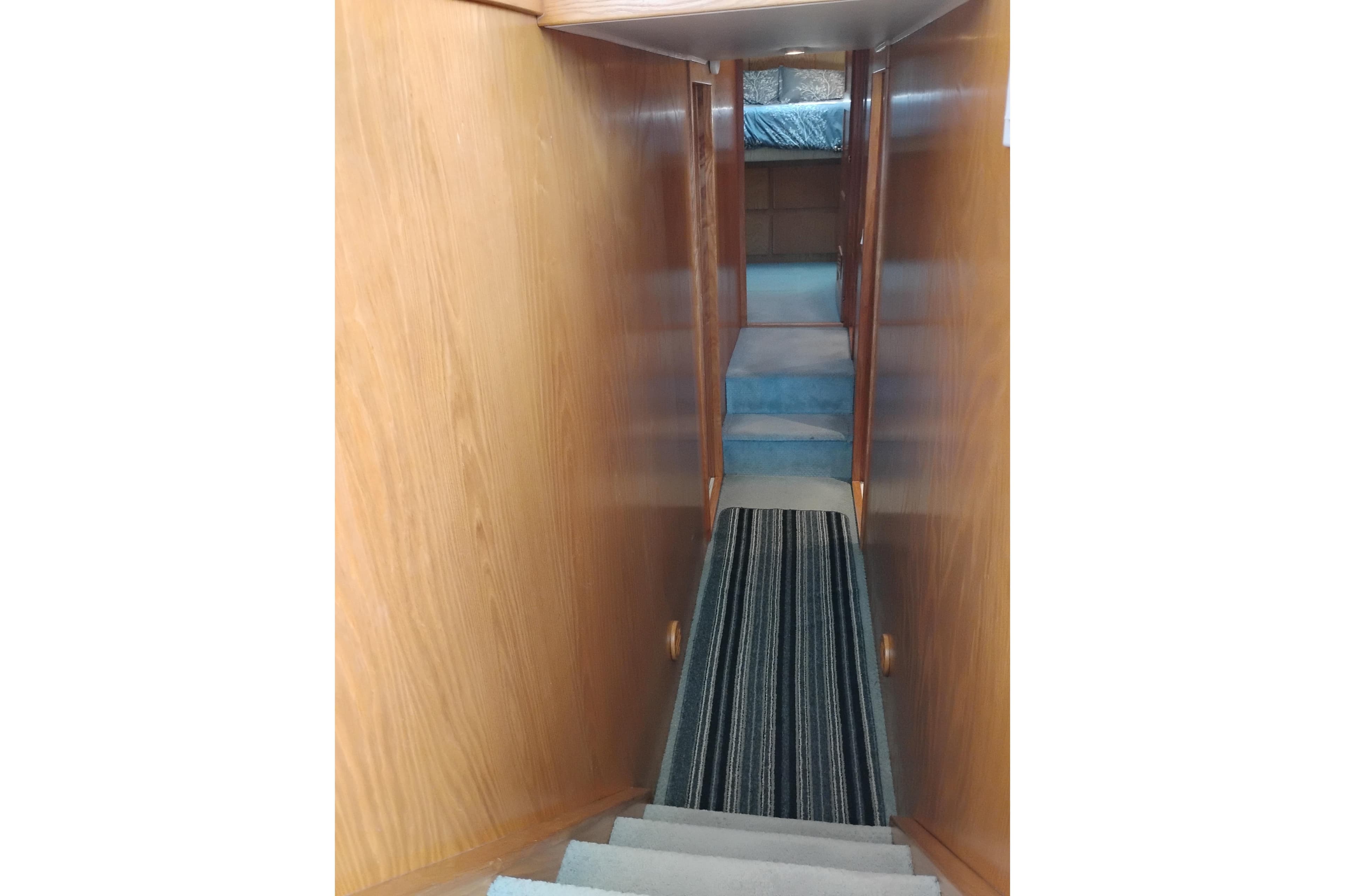 Narrow wooden hallway with striped carpet in a 1994 Navigator Classic boat.