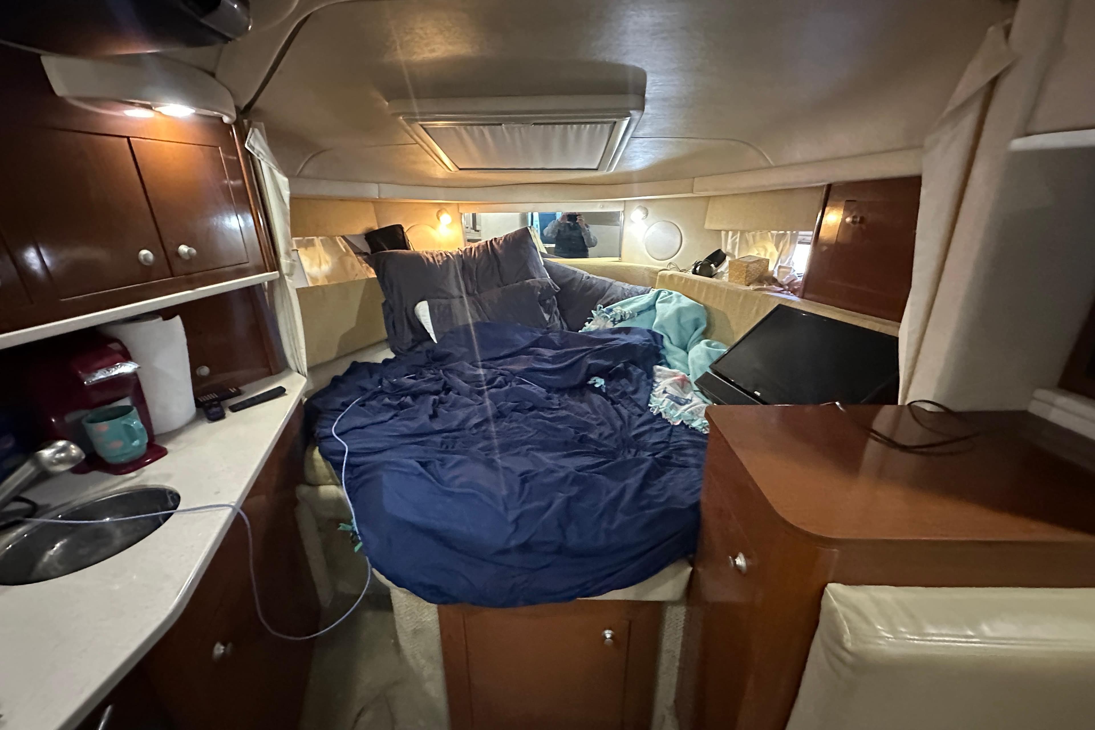 Interior cabin of 2008 Sea Ray 290 Amberjack with cozy bedding and wooden cabinetry.