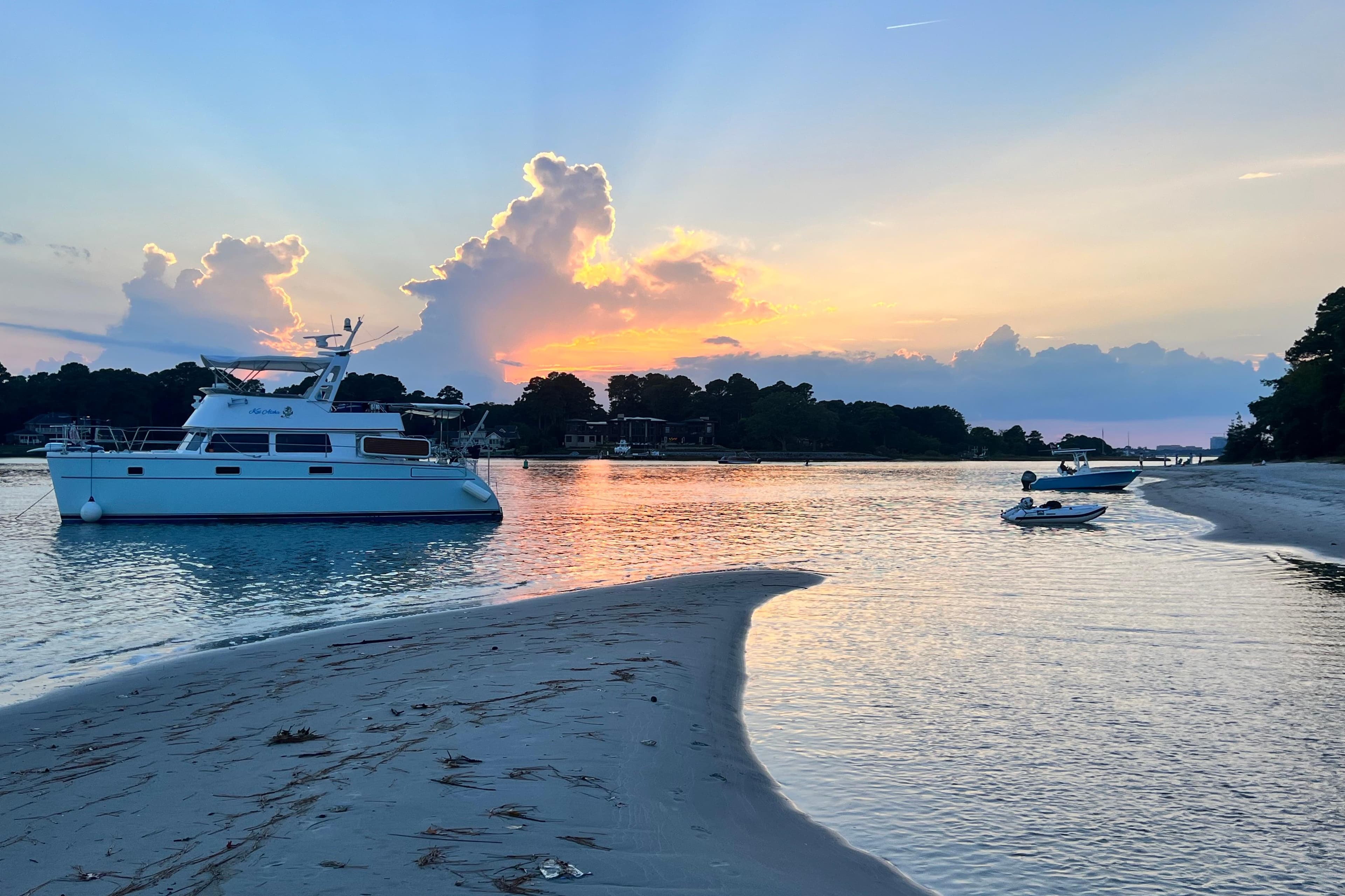Sunset over a tranquil bay with a 2007 PDQ MV41 boat anchored.