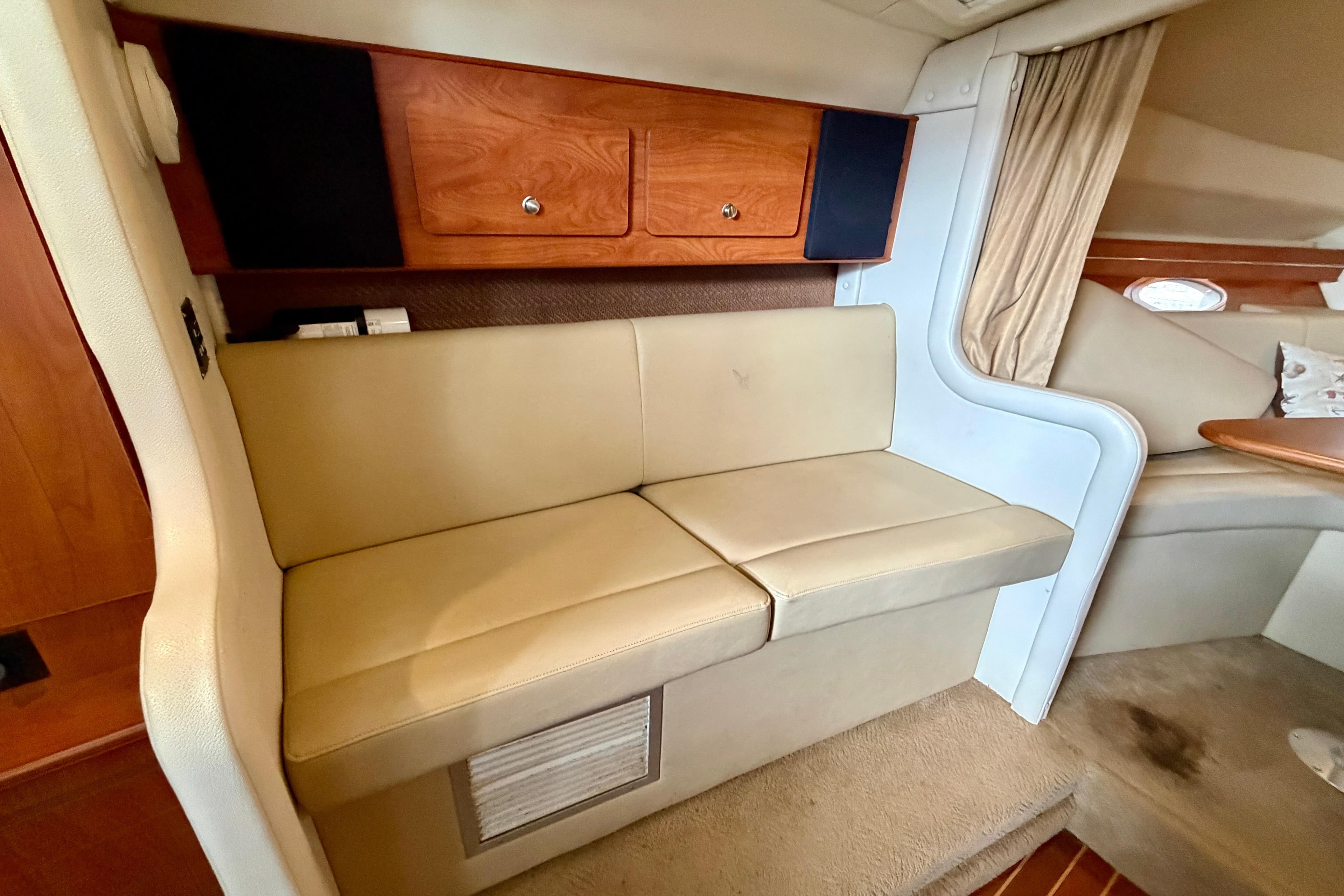 2006 Rinker 300 Express Cruiser interior with beige seating and wooden cabinetry.