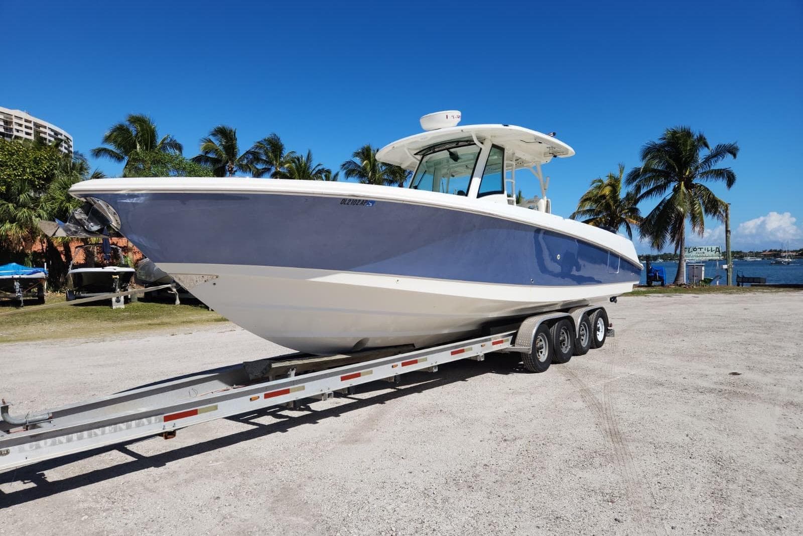 2014 Boston Whaler 350 Outrage boat on trailer, parked near palm trees and waterfront.
