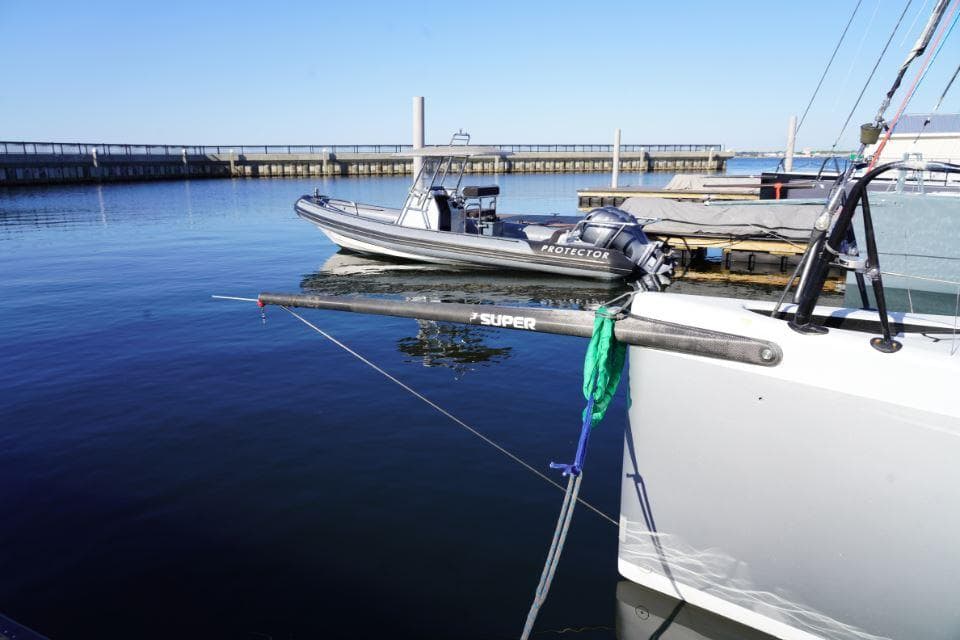 Sailboat "Judel and Vrolijk TP 52" docked near a motorboat, clear blue water.