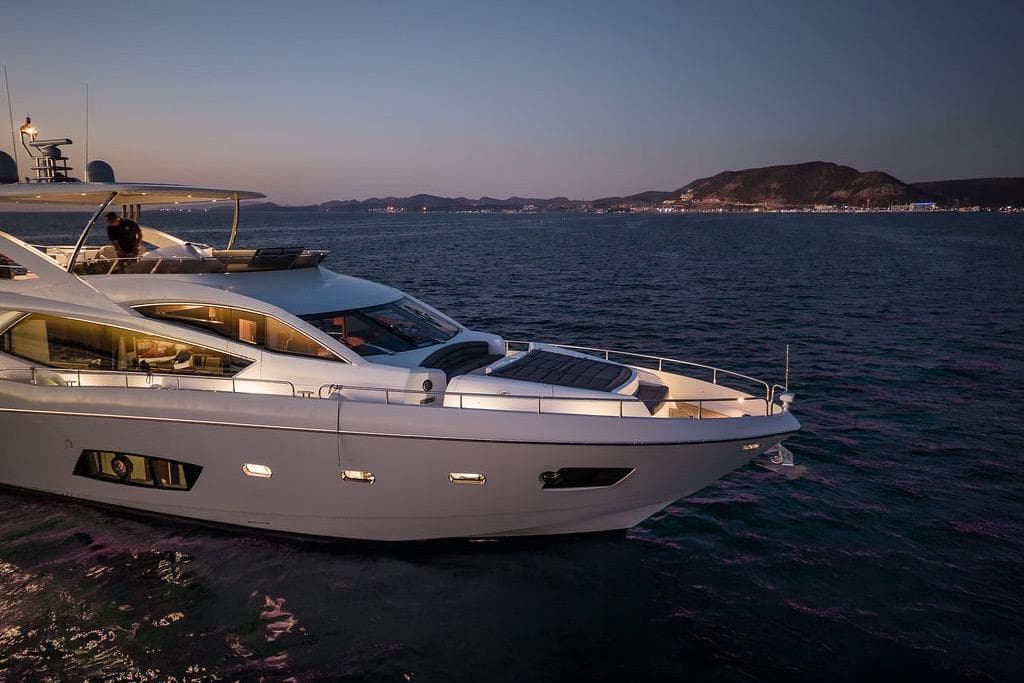 Luxurious 2012 Sunseeker Manhattan 73 yacht cruising at sunset on serene waters.