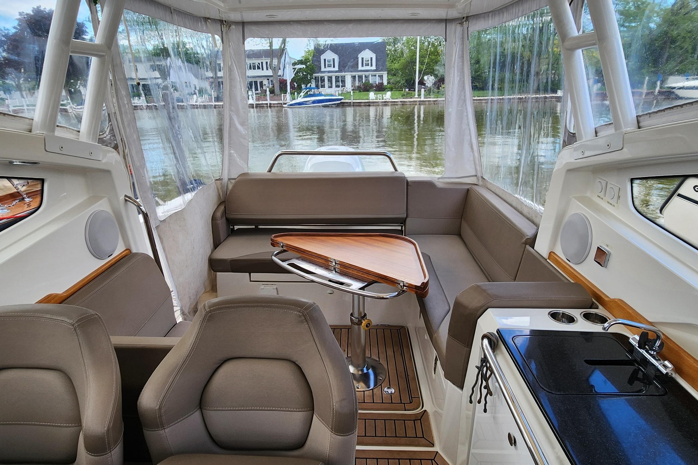 Interior of 2019 Nimbus Weekender 9 boat with seating, table, and kitchenette by the water.
