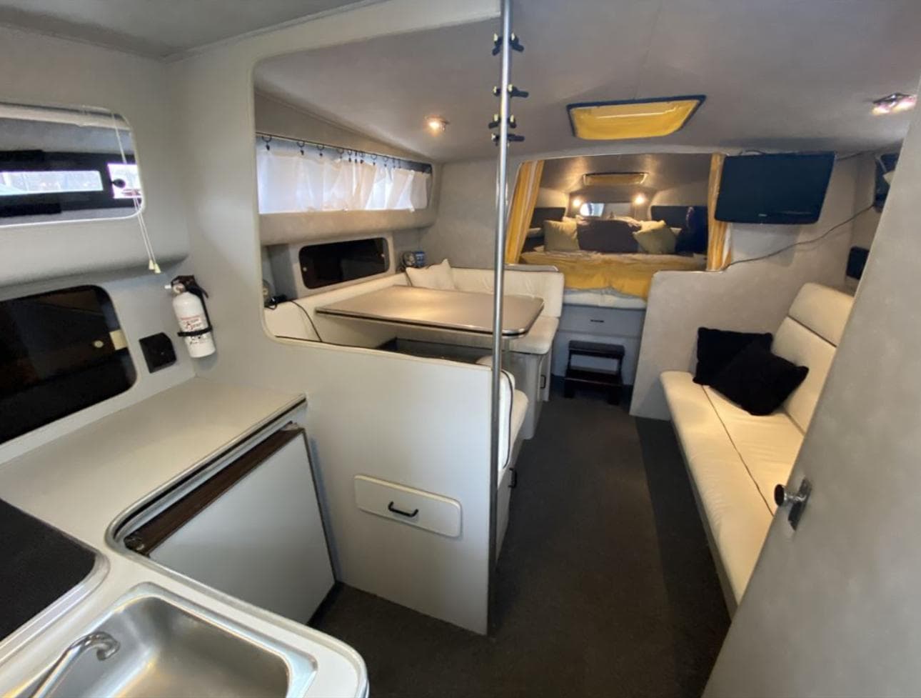 1987 Chris-Craft 320 Amerosport interior with seating, kitchenette, and cozy sleeping area.
