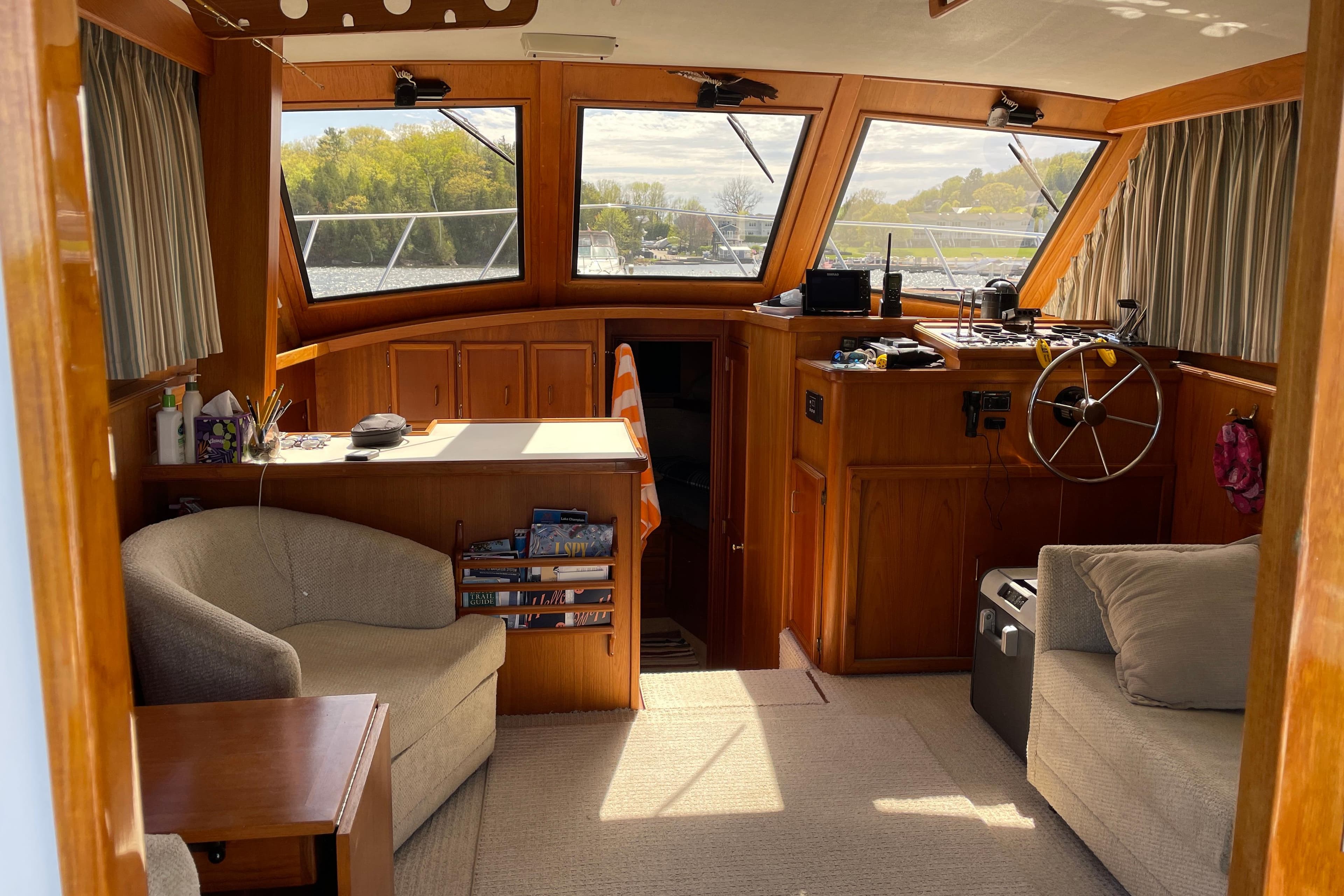 Interior of a 1984 Egg Harbor 33 Convertible boat with wooden furnishings and large windows.