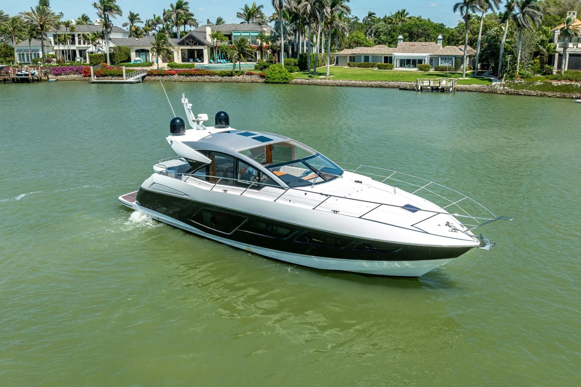 2018 Sunseeker Predator 57 yacht cruising on a serene waterway with luxury homes in the background.