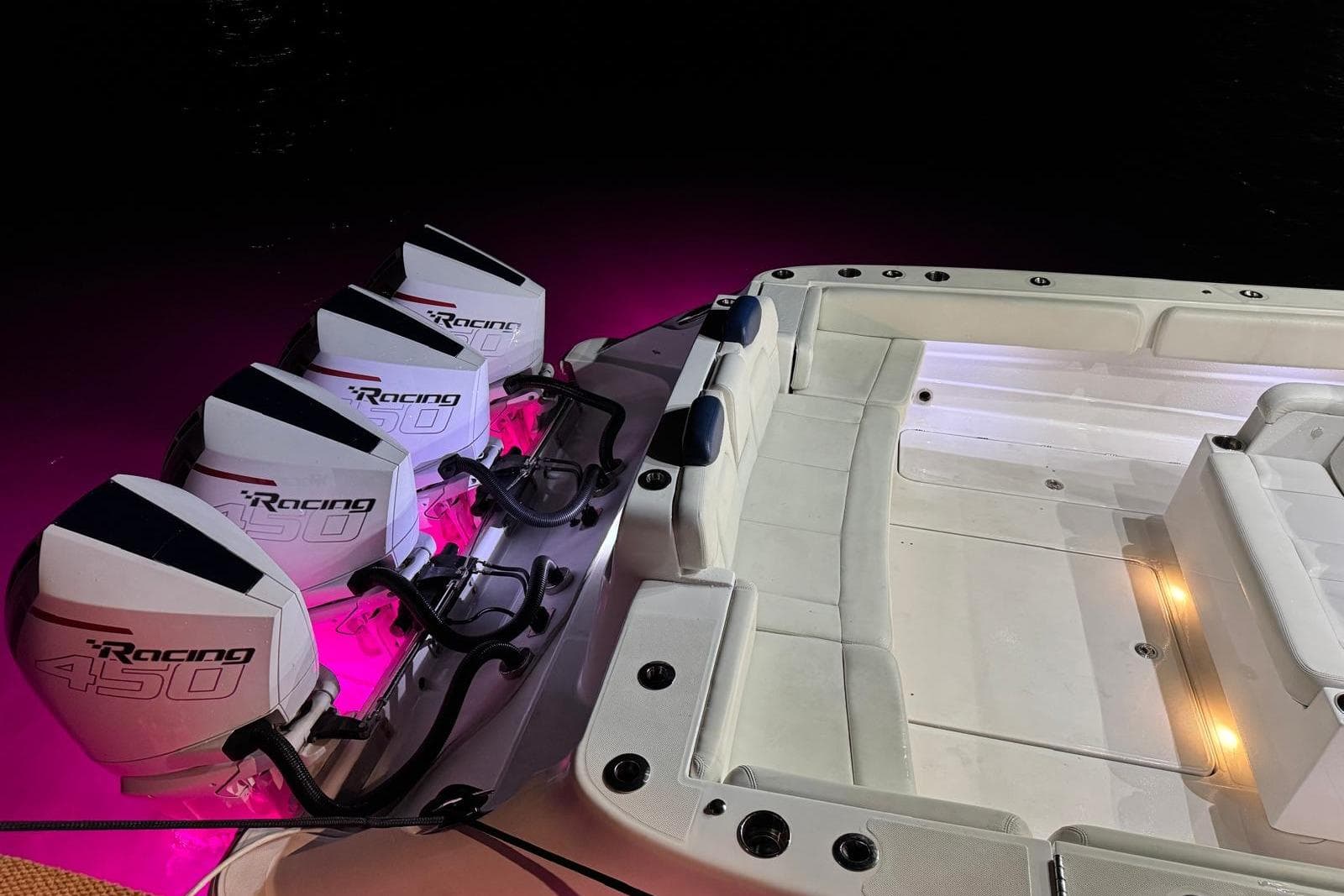 2021 HCB 42 Lujo boat with quad Racing 450 engines, illuminated by pink lights.