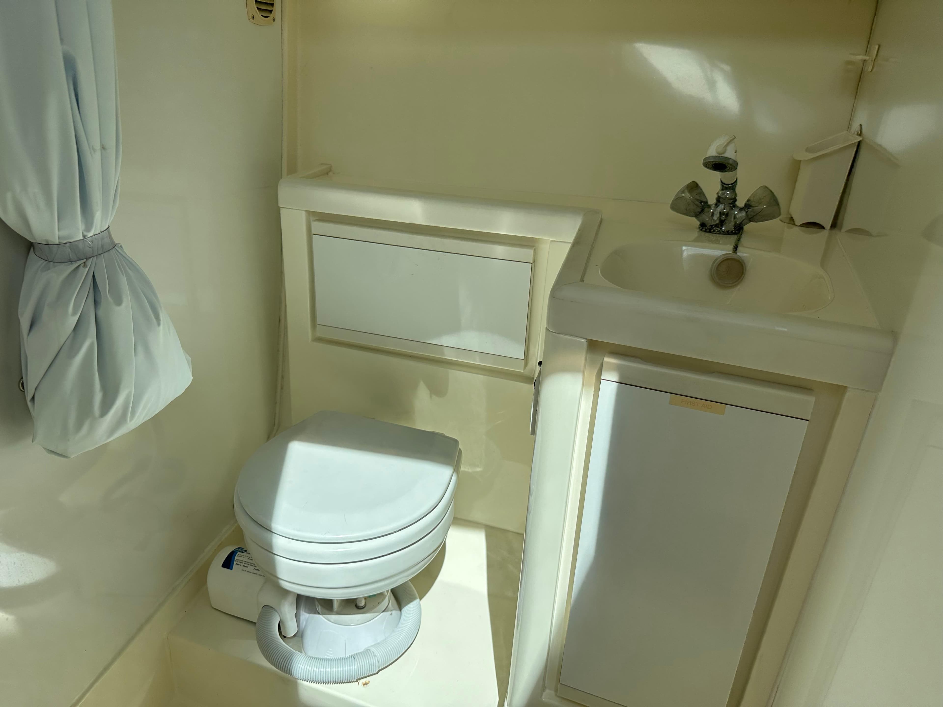 1994 Bertram 30 Express Fisherman boat bathroom with toilet, sink, and storage cabinet.