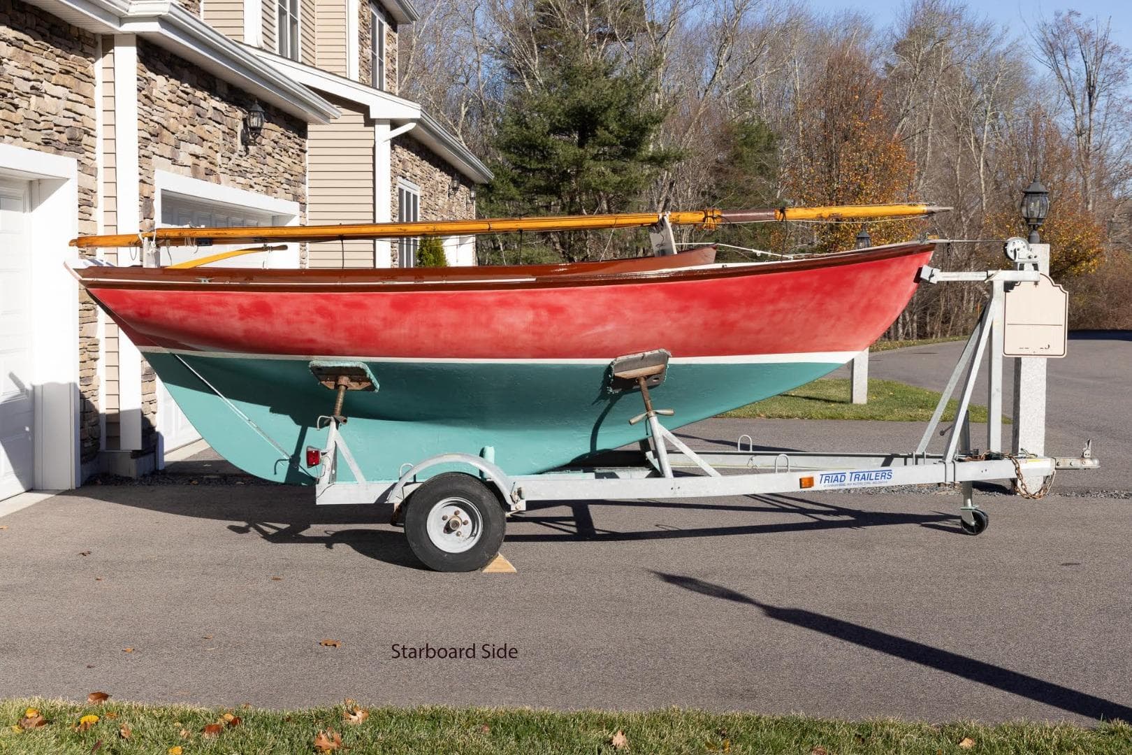 Red and teal Herreshoff 12 sailboat on trailer, Cape Cod Shipbuilding, 2002 model.