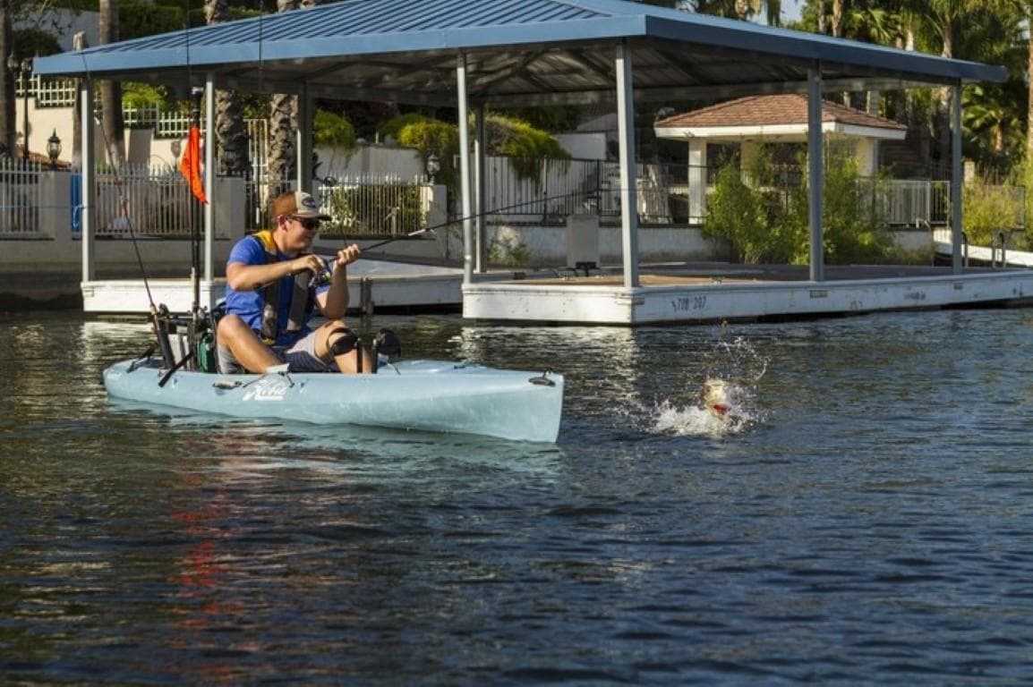 Man fishing from a 2023 Hobie Revolution 13 kayak on a calm lake.