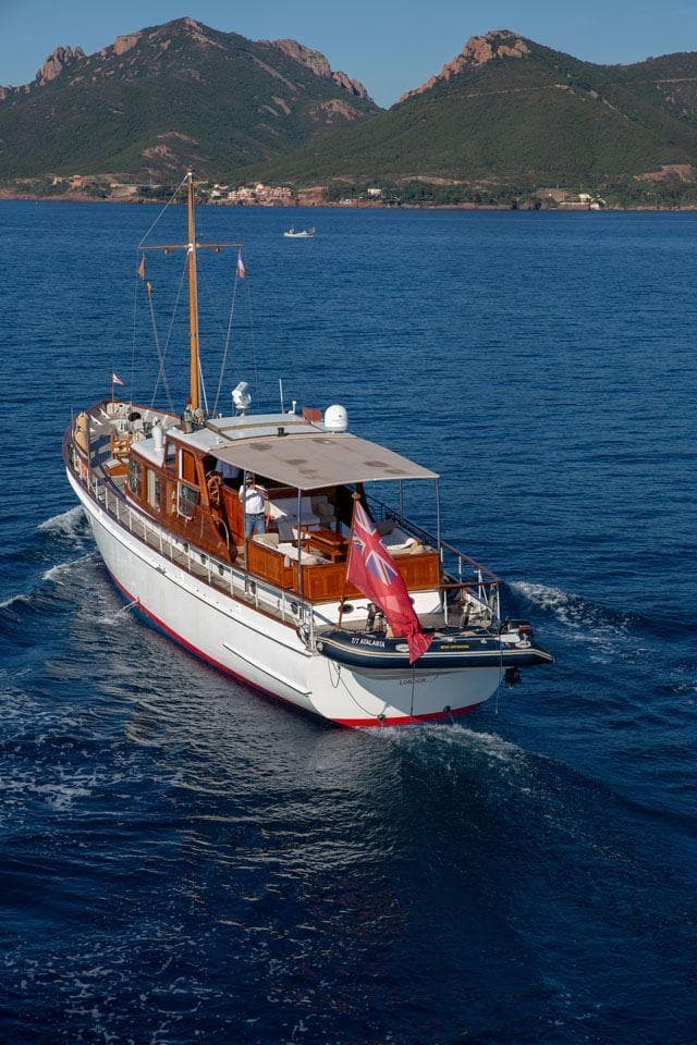 Vintage 1958 Feadship Custom 25m yacht cruising in scenic coastal waters.