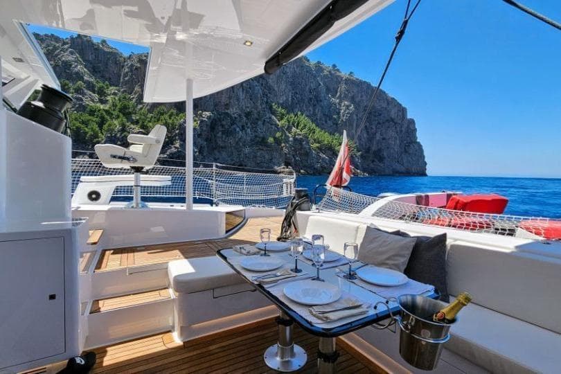 Luxurious 2016 HH Catamarans HH66 yacht with elegant dining setup, scenic ocean view.