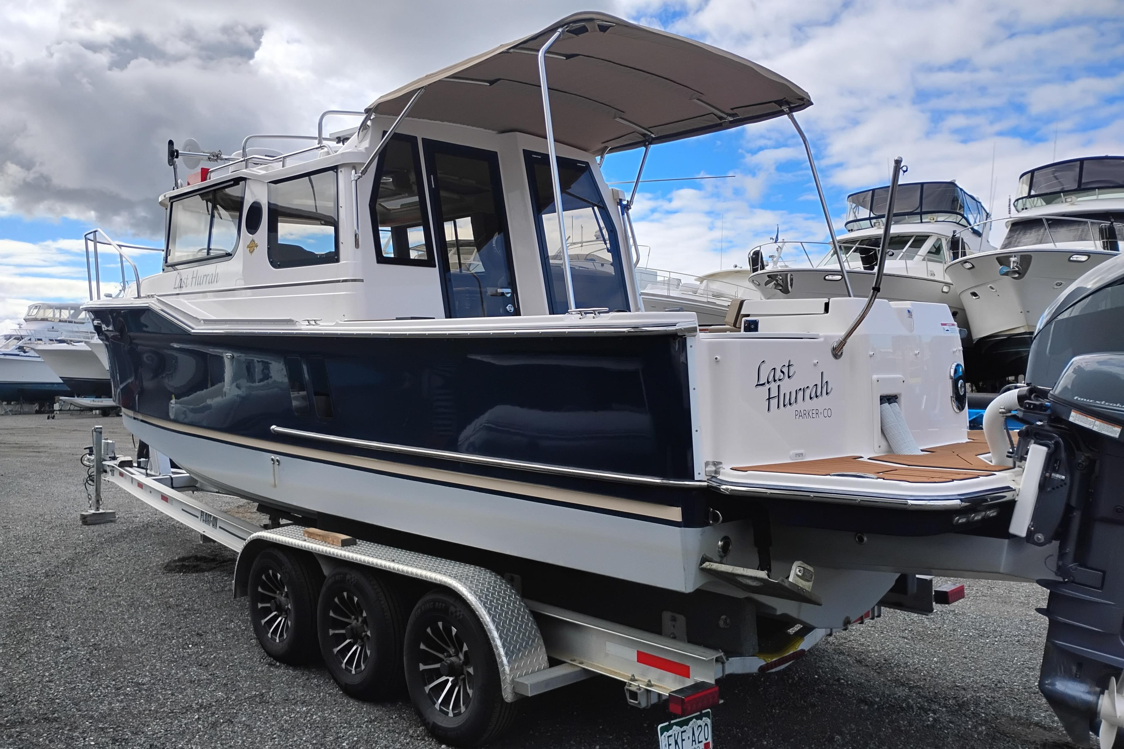 2024 Ranger Tugs R-27 boat on trailer, parked outdoors under cloudy sky.