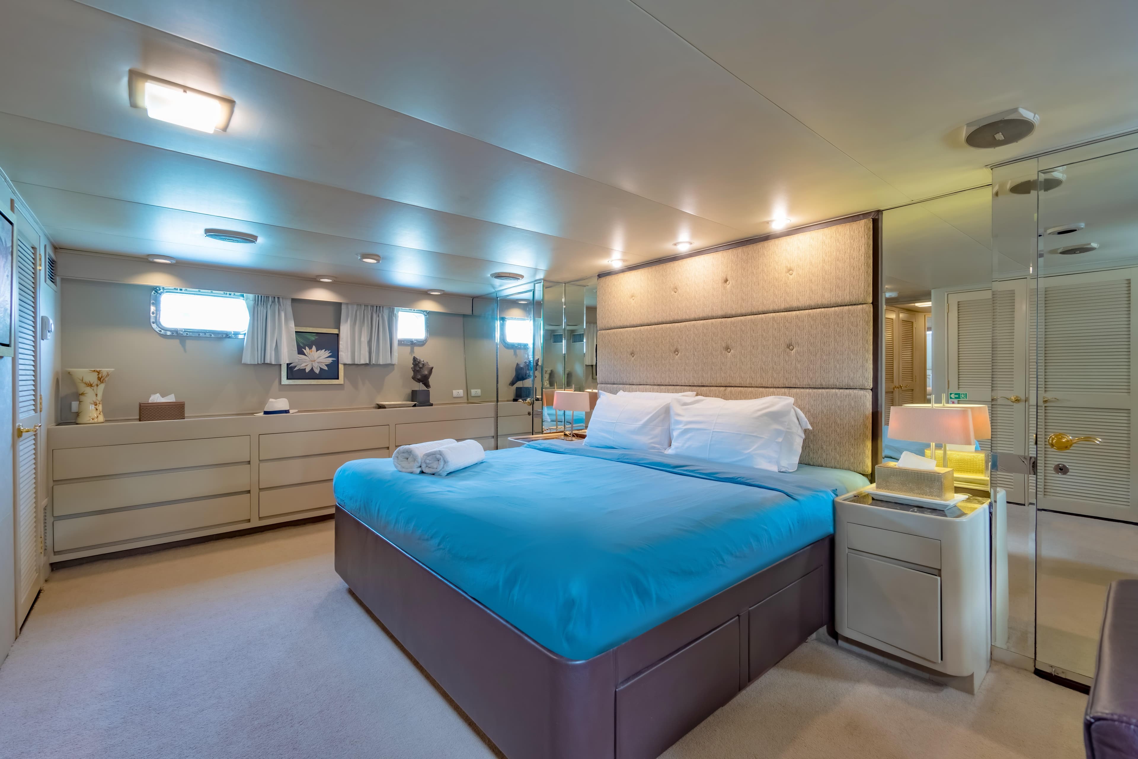 Luxurious bedroom interior on 1984 Broward 33m yacht with blue bedding and modern decor.