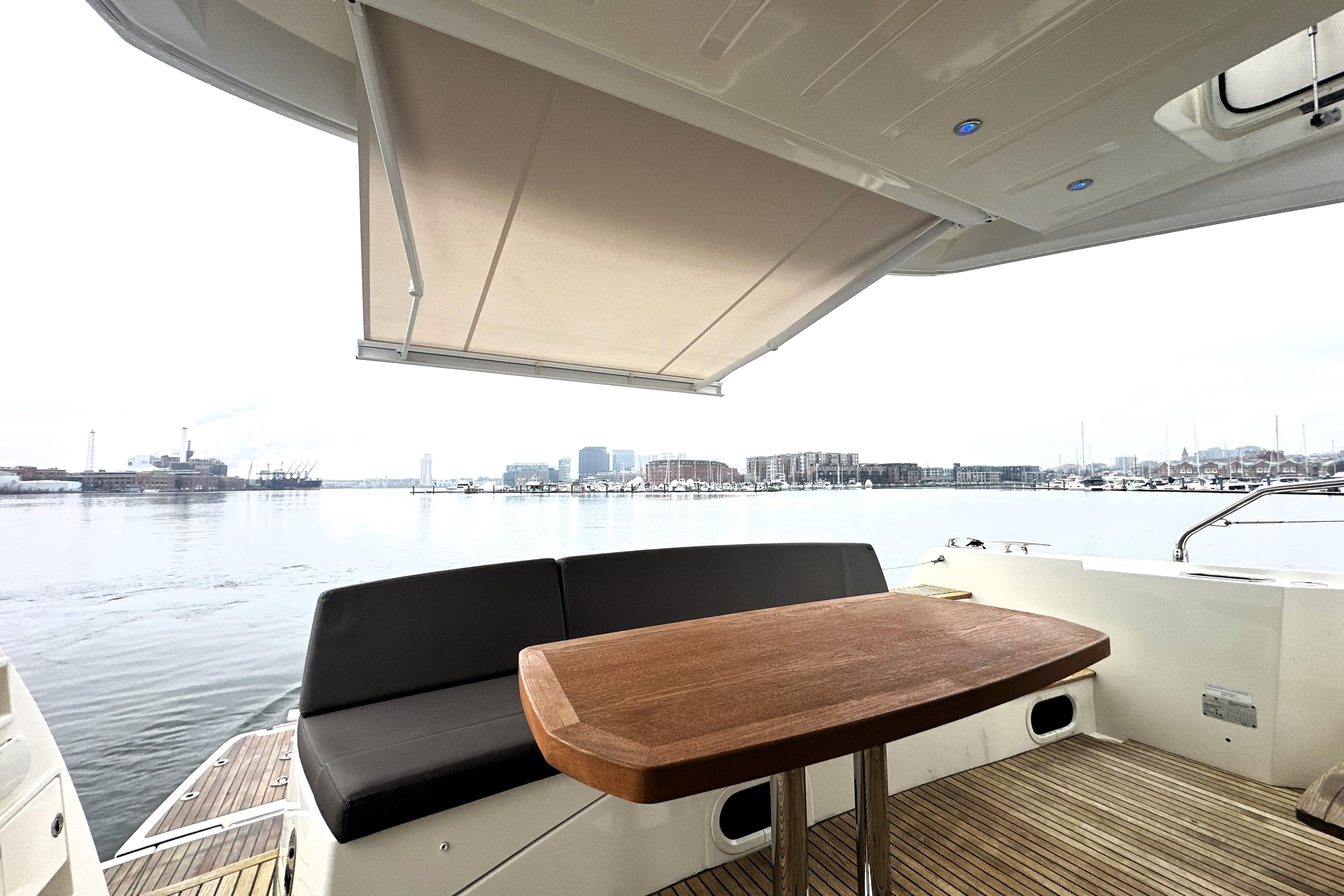 Luxury yacht deck with seating and table, Prestige 500, 2017 model, overlooking a serene waterfront.