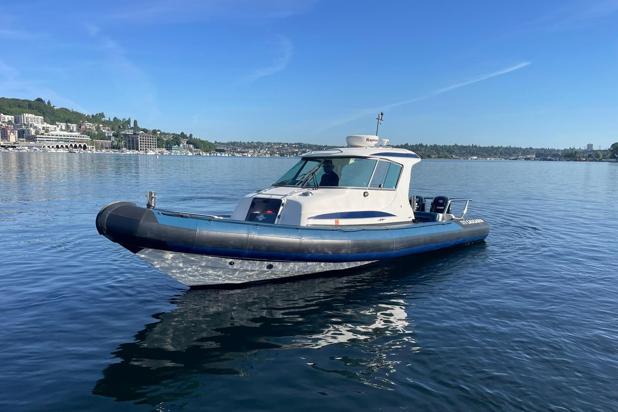 2004 Protector Targa 28 boat on calm water with scenic shoreline background.