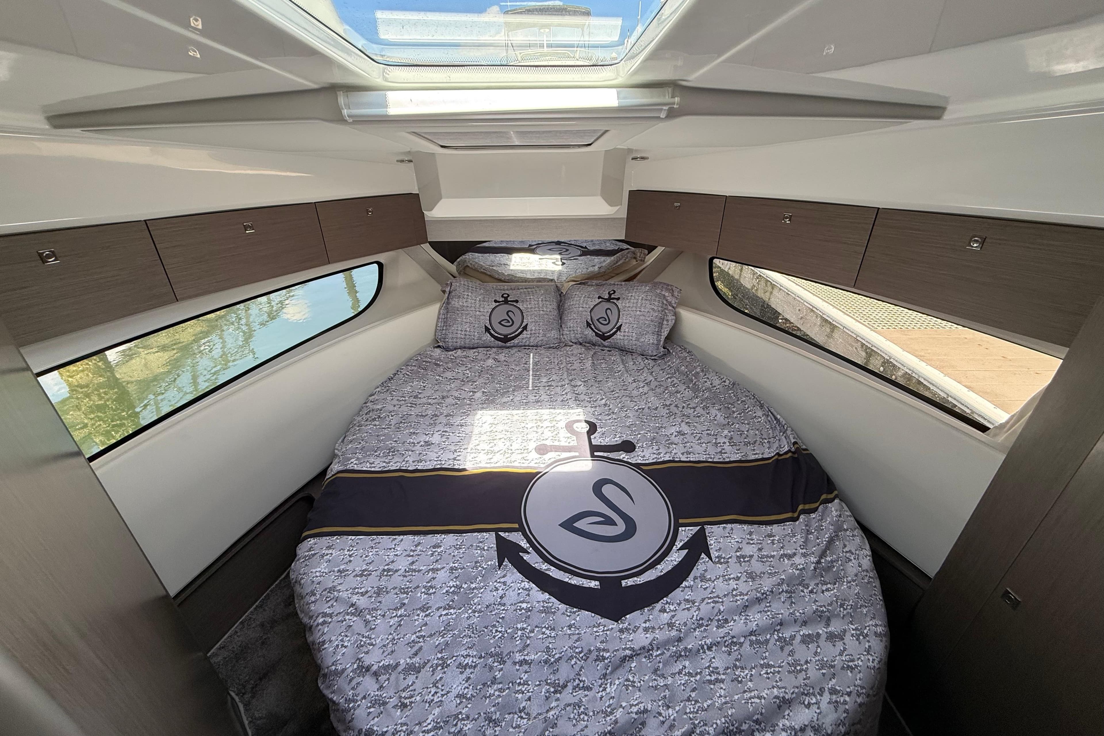 2024 Jeanneau NC 1095 Coupe cabin interior with stylish bedding and ample natural light.