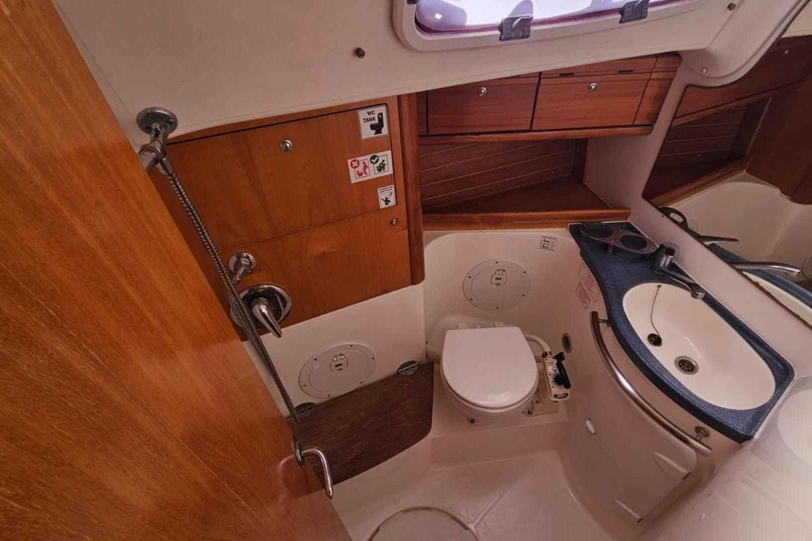 Interior of 2006 Bavaria Cruiser 50 yacht bathroom with sink, toilet, and wooden cabinetry.