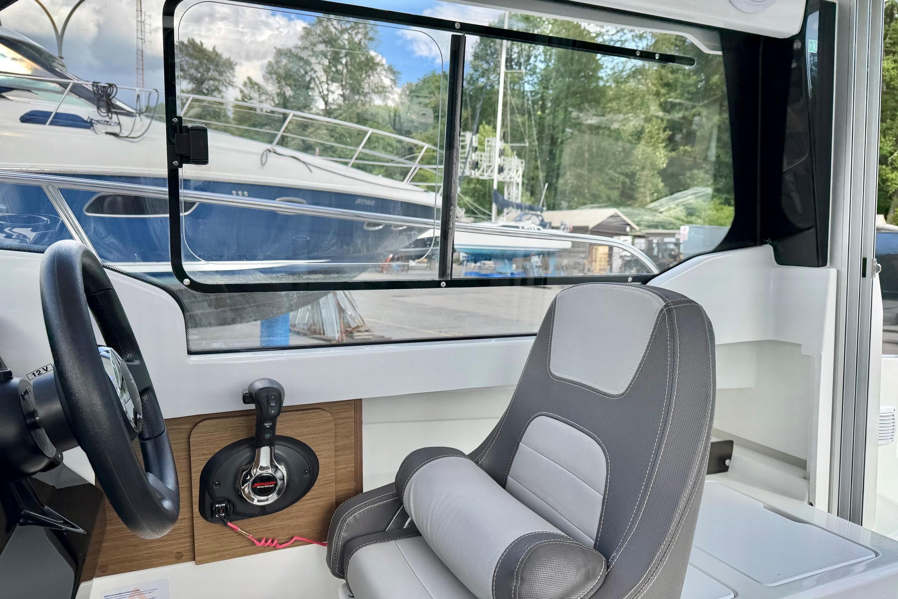 Interior of 2023 Jeanneau NC Sport 695 Series 2 boat, featuring steering wheel and seat.