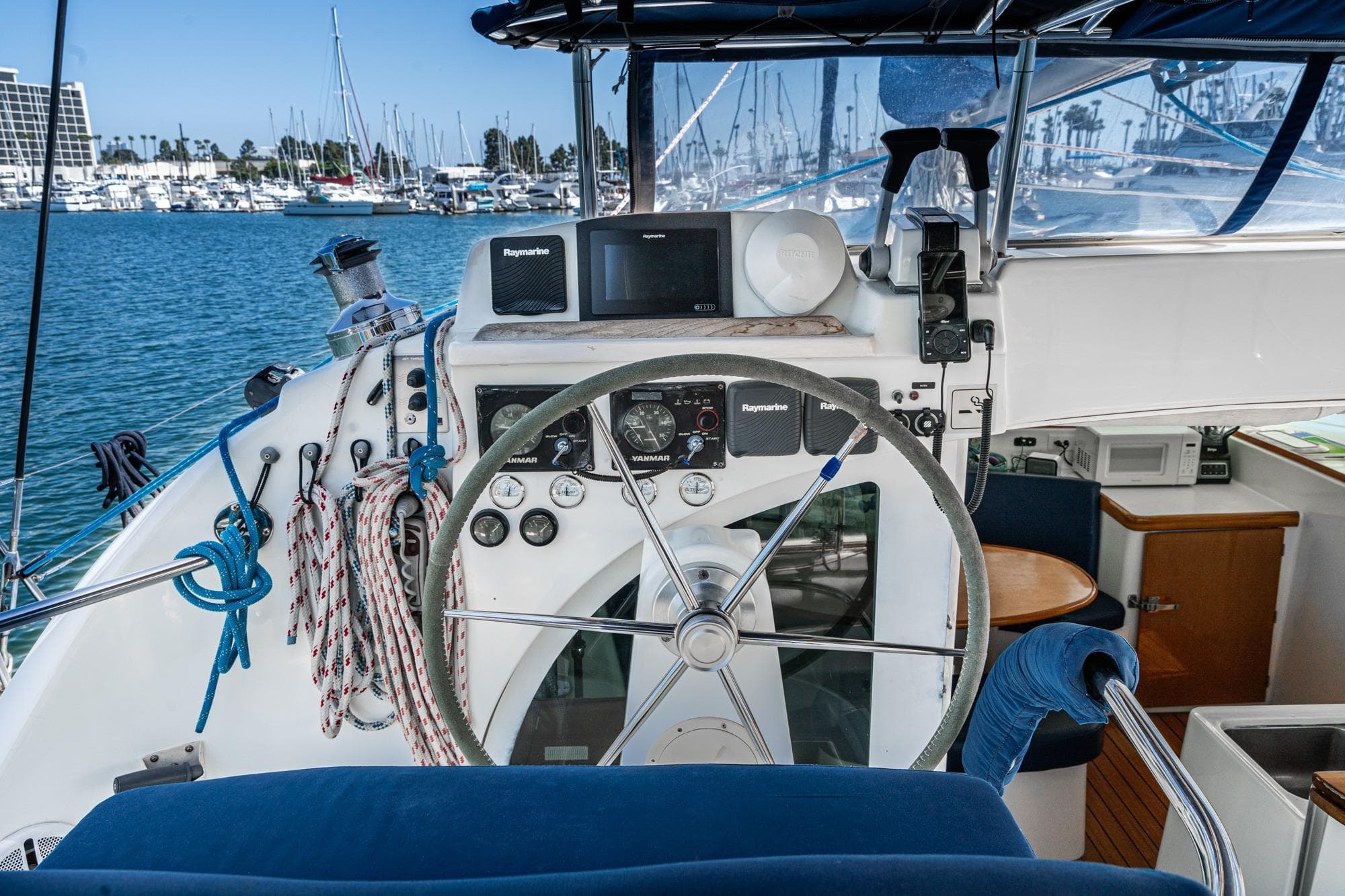 Helm of 2004 Lagoon 380 catamaran with navigation equipment and marina view.