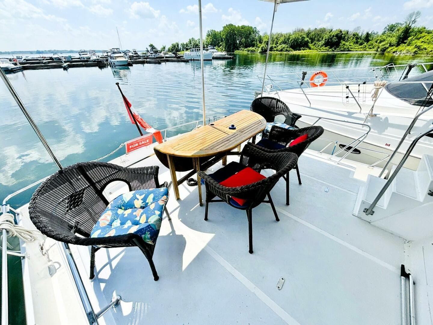 1985 DeFever 40 Offshore yacht deck with wicker chairs and table, docked by calm waters.